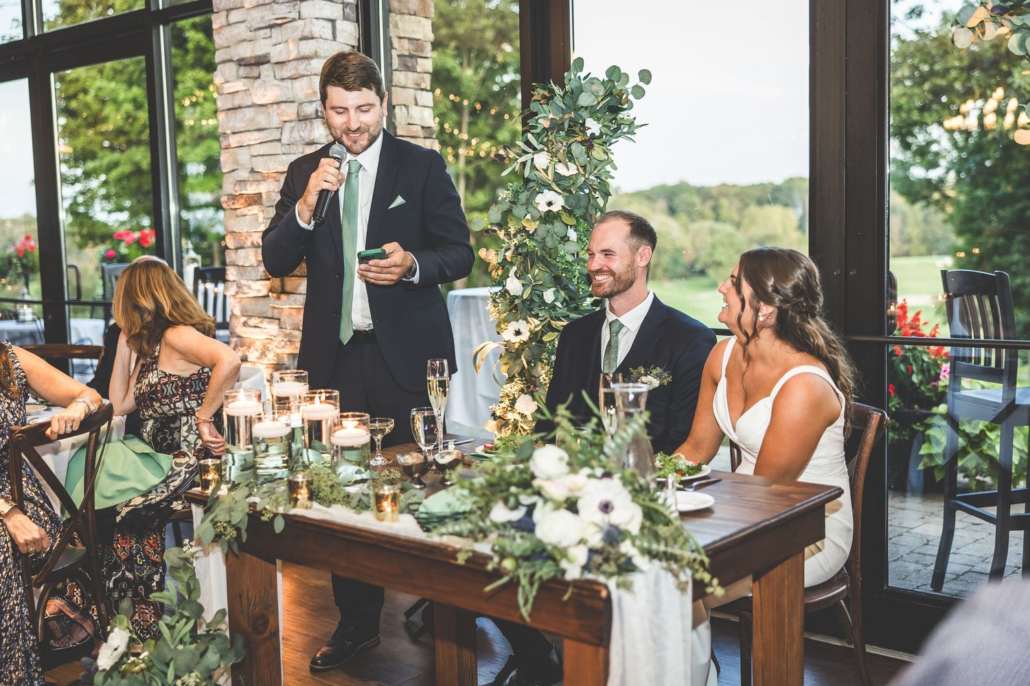 Wedding celebration in a rustic venue with stone walls and large windows.