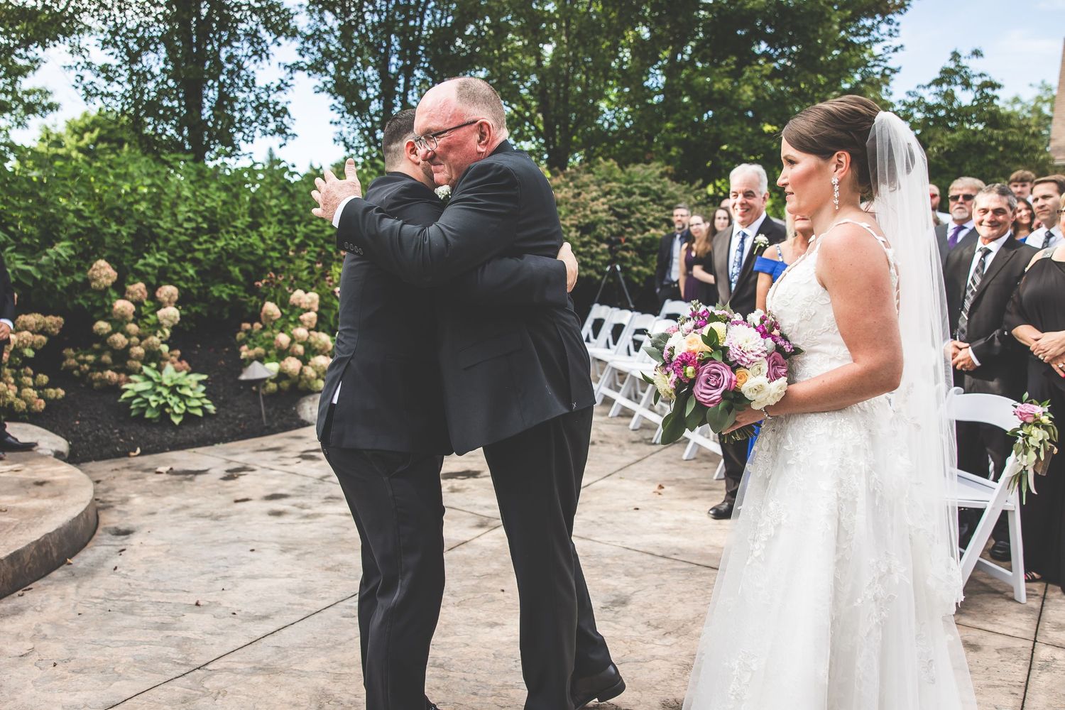 Wedding ceremony procession taking place on outdoor stone pathway.