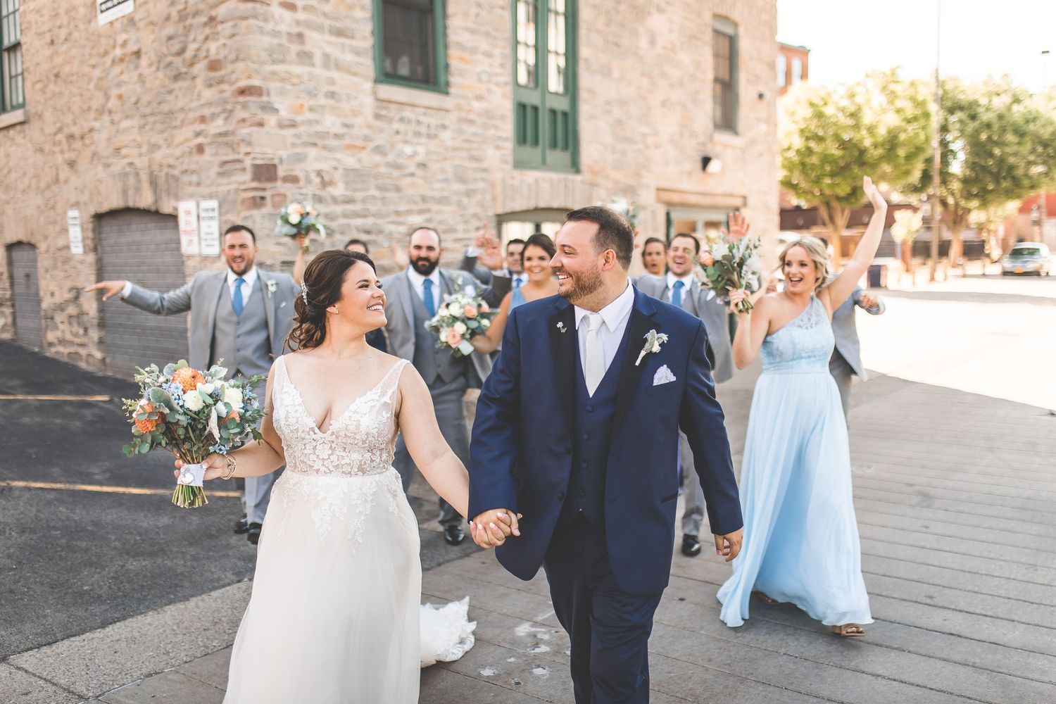 Wedding party walking together outside historic brick building.