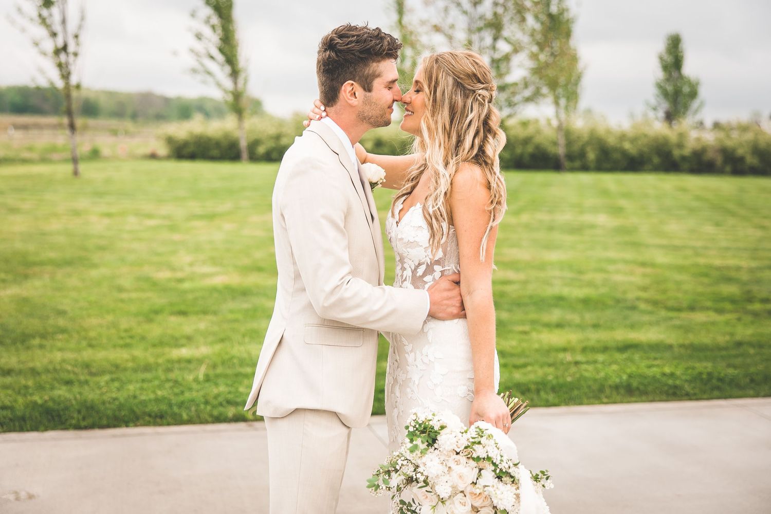 Romantic wedding couple embraces in an outdoor garden setting with soft natural lighting.