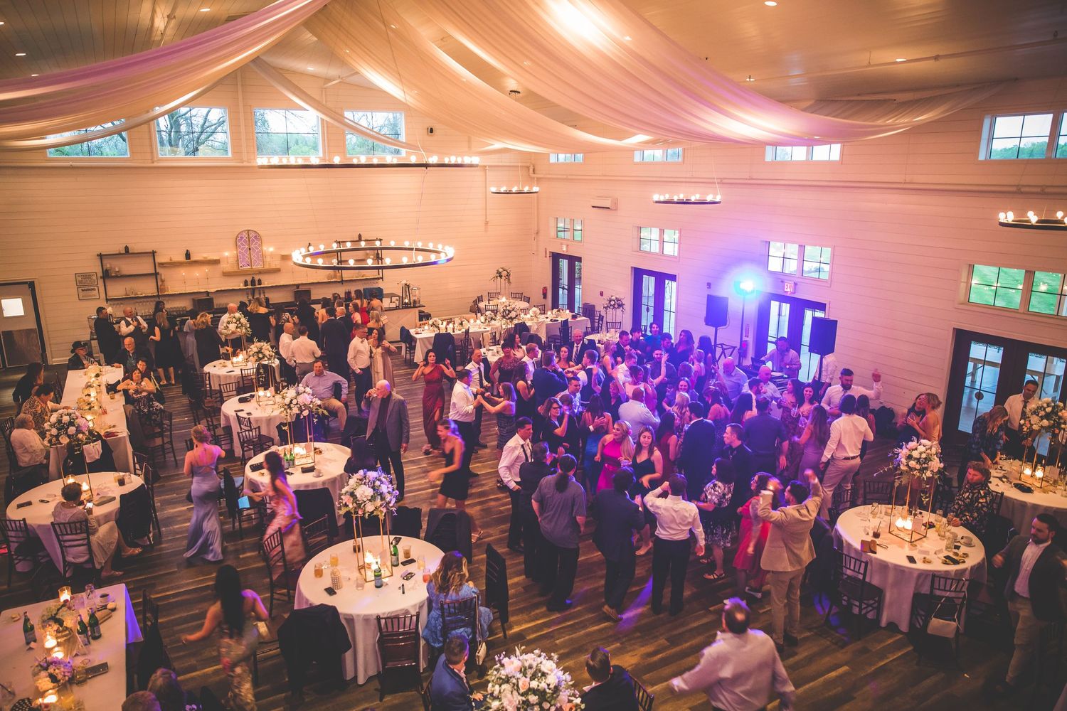 An overhead view of a wedding reception venue with round tables and a packed dance floor.