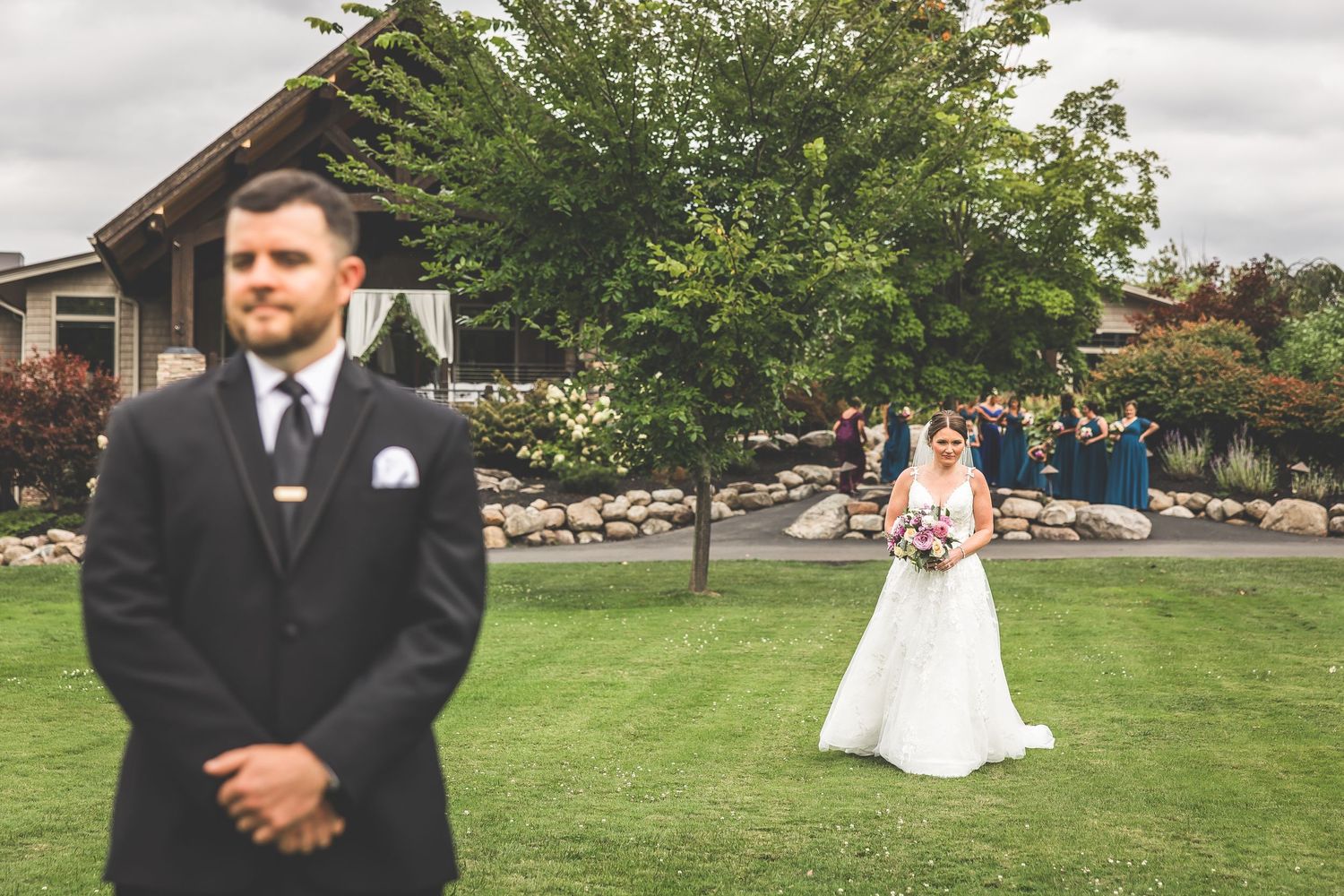 Outdoor wedding photography session on a lush green lawn with overcast skies.