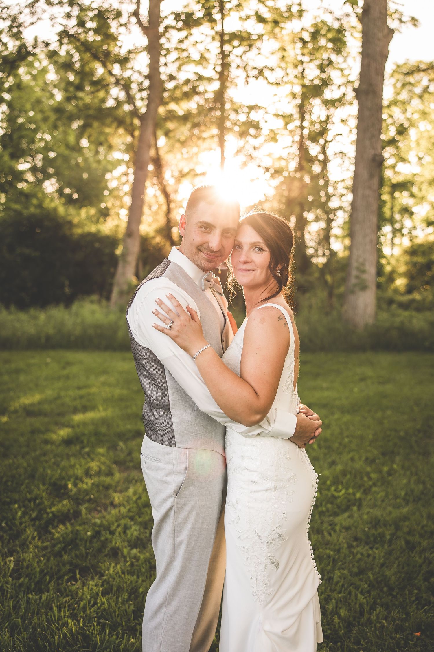 Romantic sunset wedding portrait in a lush green garden setting.