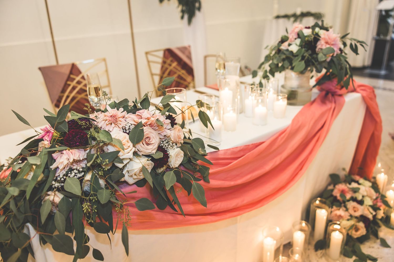 Wedding reception decor featuring pink drapery and floral arrangements on tables.