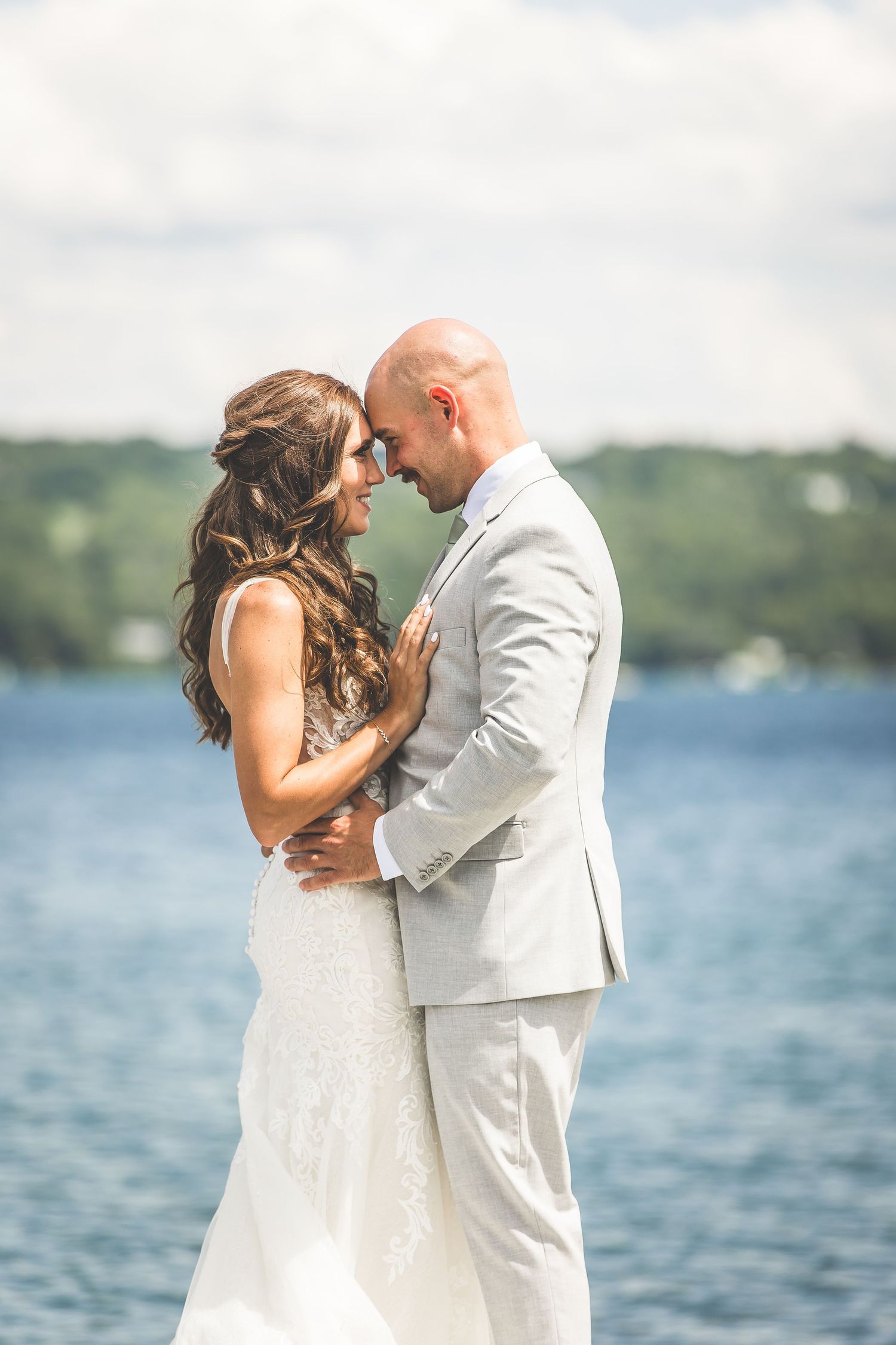A romantic wedding couple embraces by a serene lakeside on their special day.