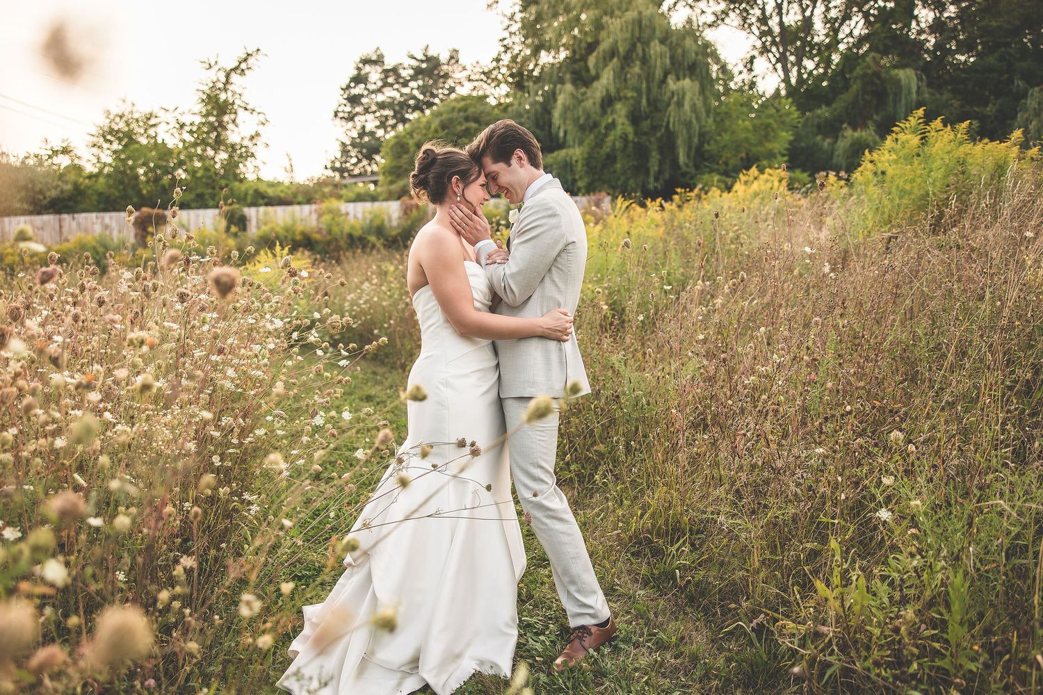 Couple embraces lovingly among wildflowers during rustic outdoor wedding session.
