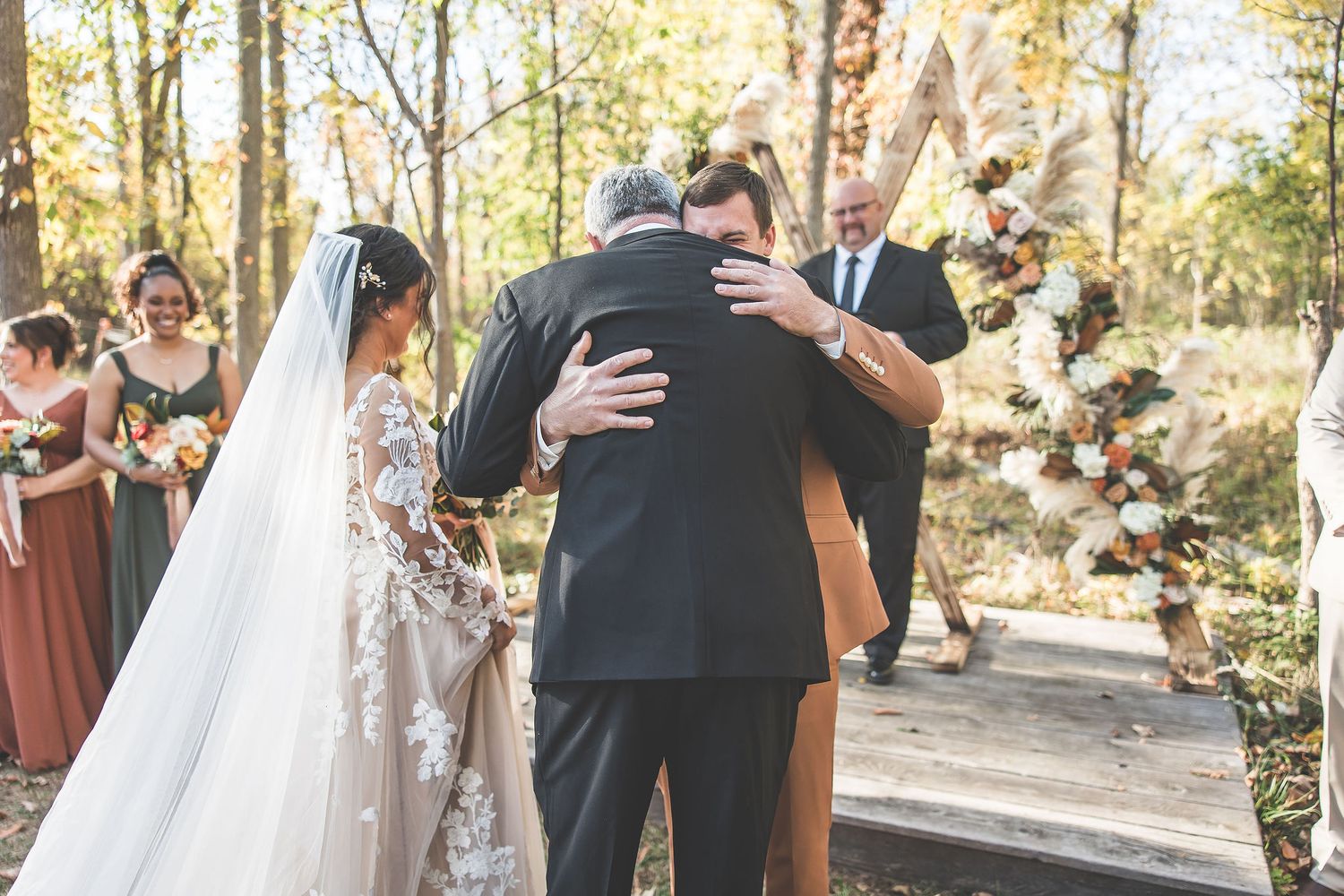 Wedding ceremony procession moves through an outdoor wooded venue.