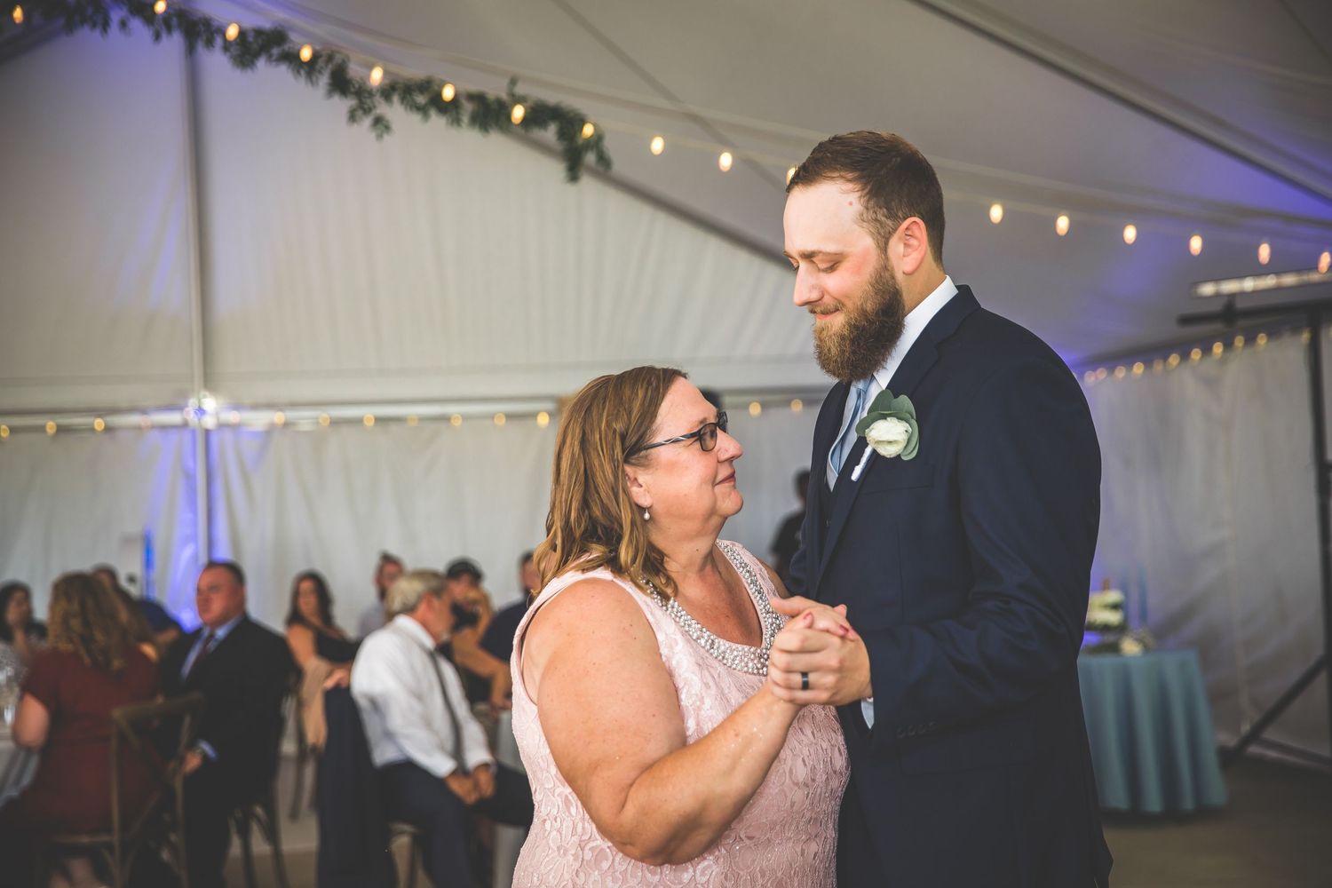 Joyful dancing moments captured during a wedding reception in an elegant tented venue.