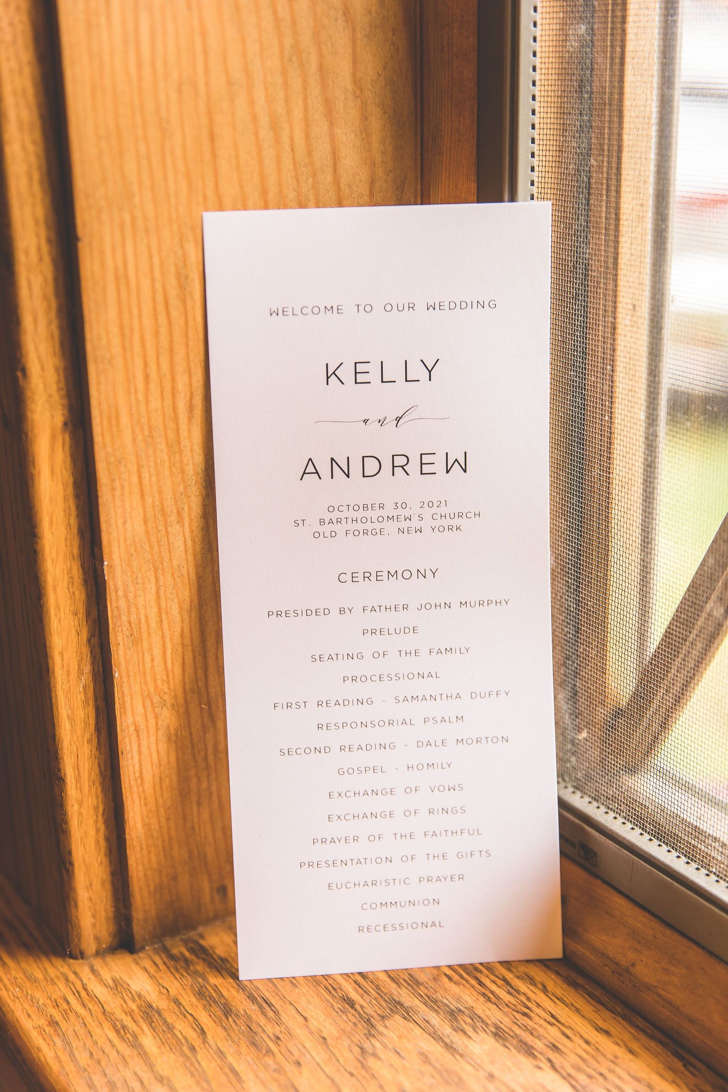 Wedding ceremony program cards displayed on wooden windowsill.