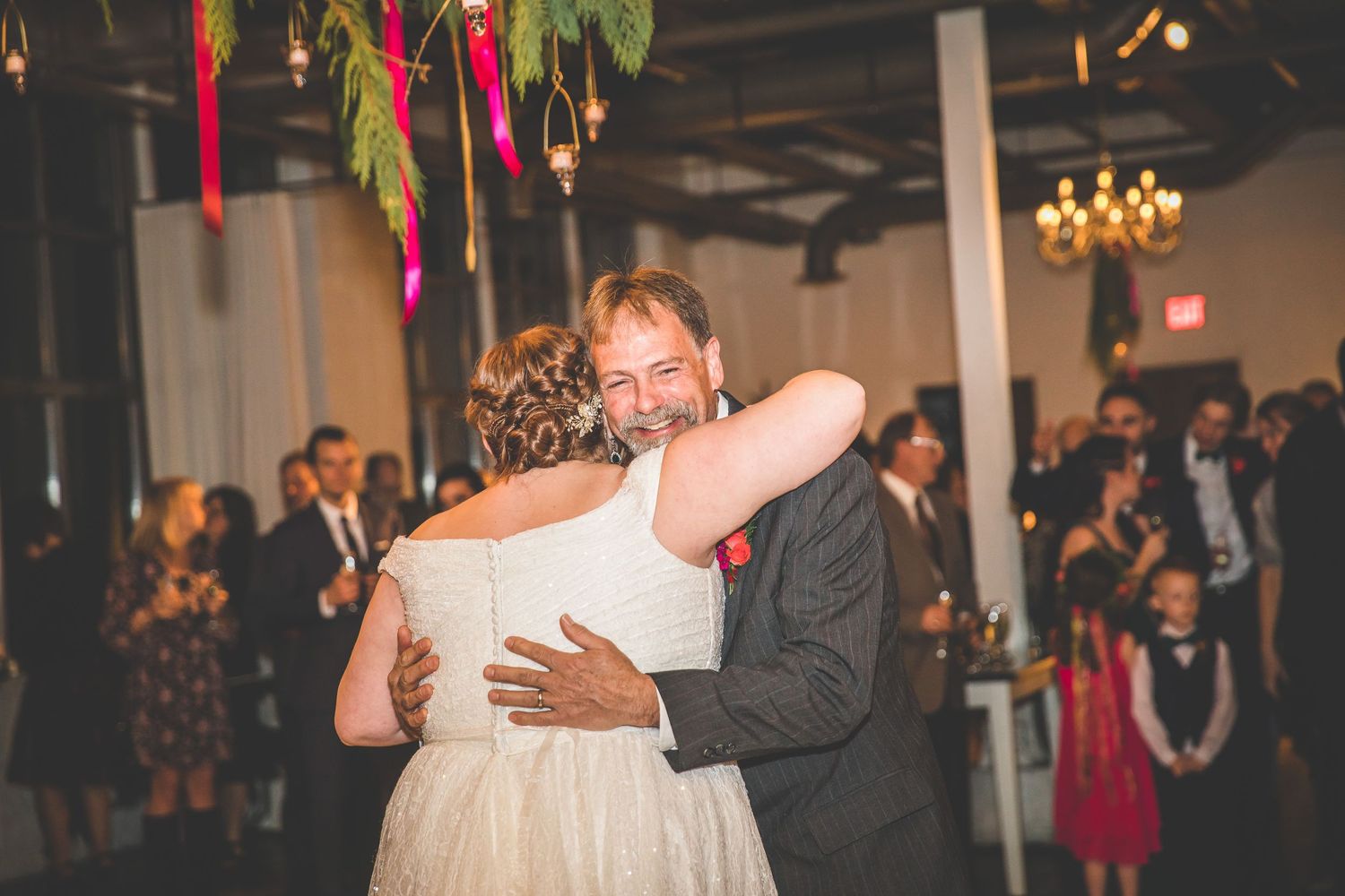 Wedding guests dancing beneath festive decorations and string lights at evening reception.