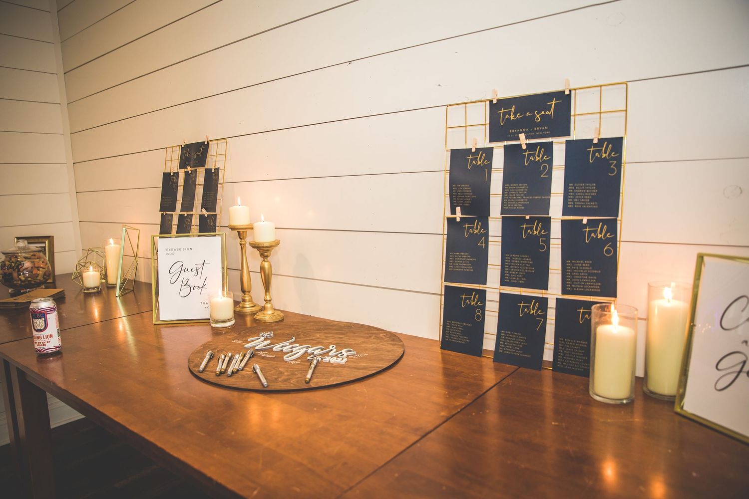 Rustic wedding venue details showing candles and decor elements arranged on wooden tables in warm lighting.