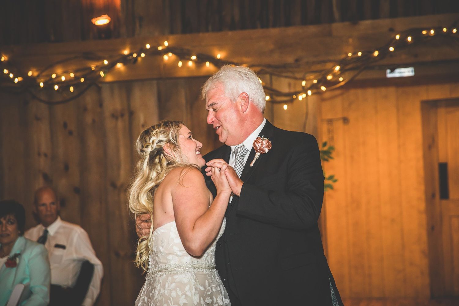 Couples dancing together at a rustic barn wedding reception with string lights overhead.