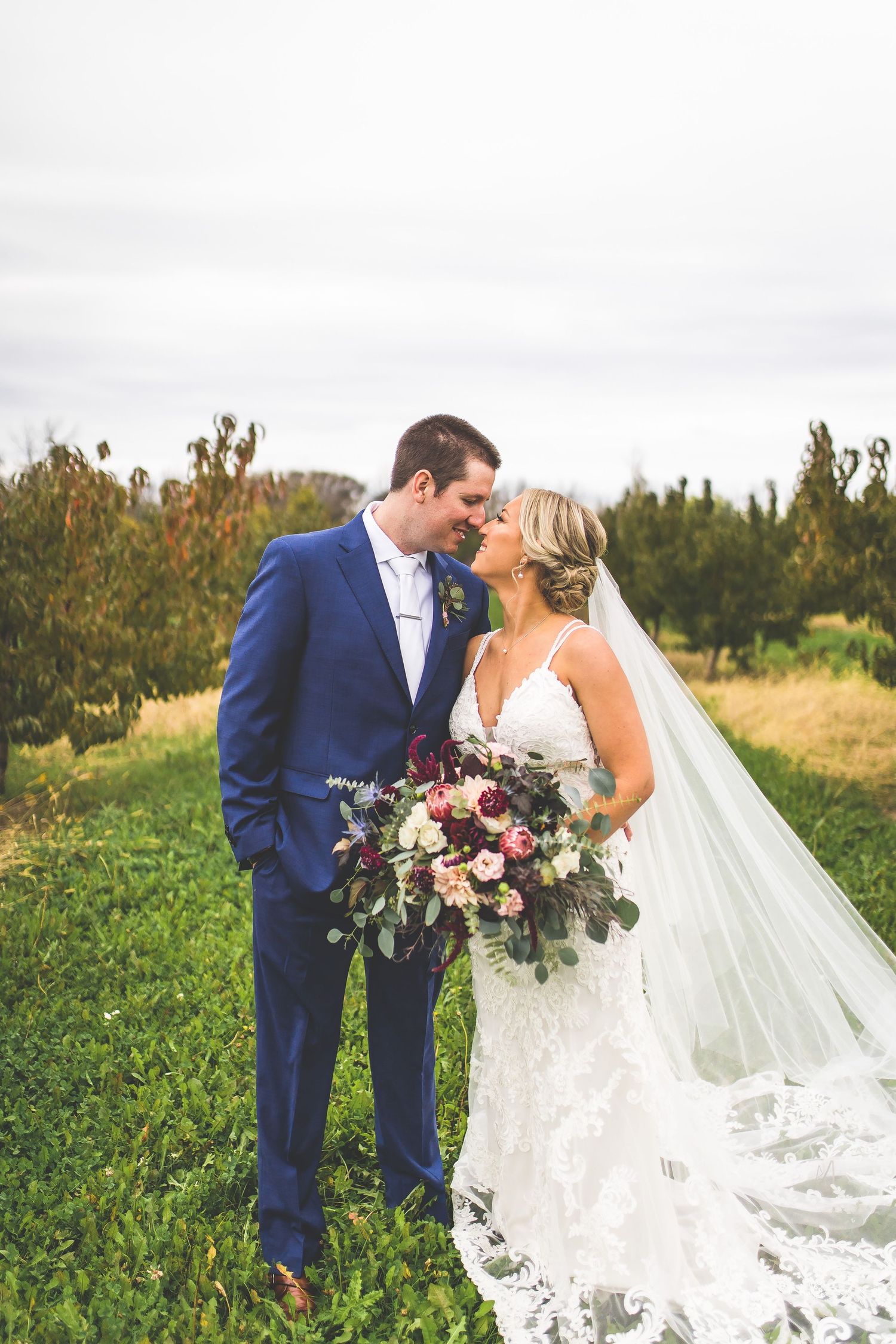 Couple shares intimate wedding day moments in a lush garden setting with dramatic veil.