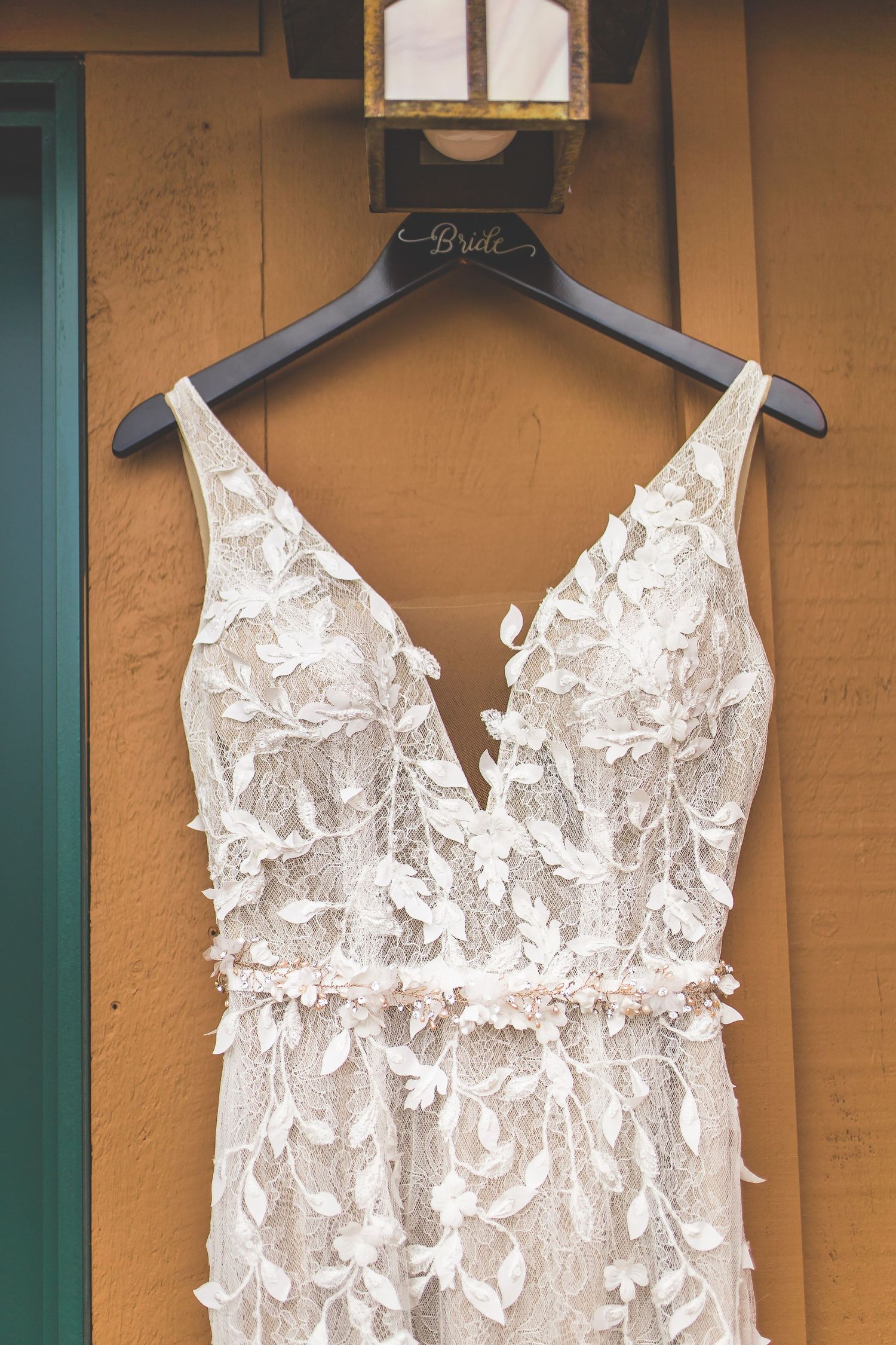 Elegant white lace wedding dress with delicate floral details hanging on display.