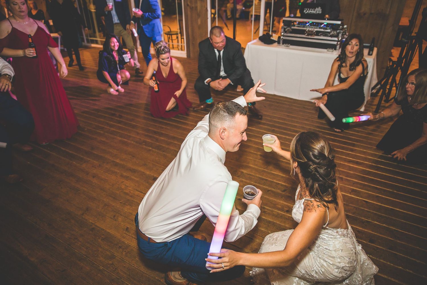 Lively reception party scene with guests dancing in a barn-style venue with string lights.