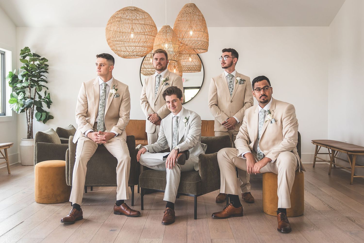 Wedding party relaxing on modern furniture in a bright room with pendant lights and plants.