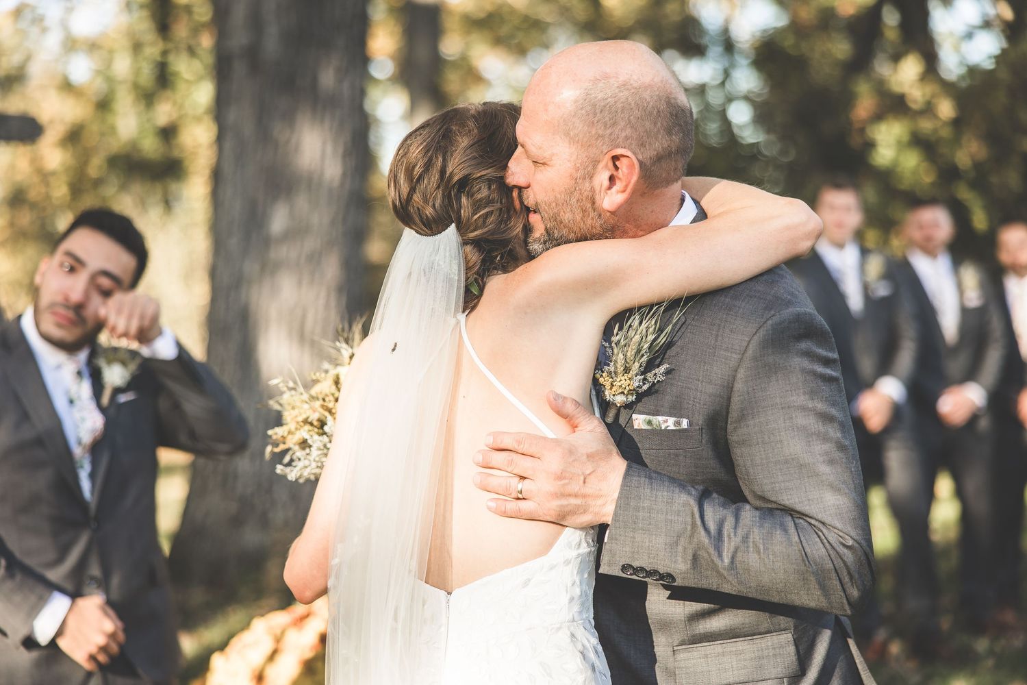 An emotional embrace captured during a wedding ceremony with guests looking on in the background.