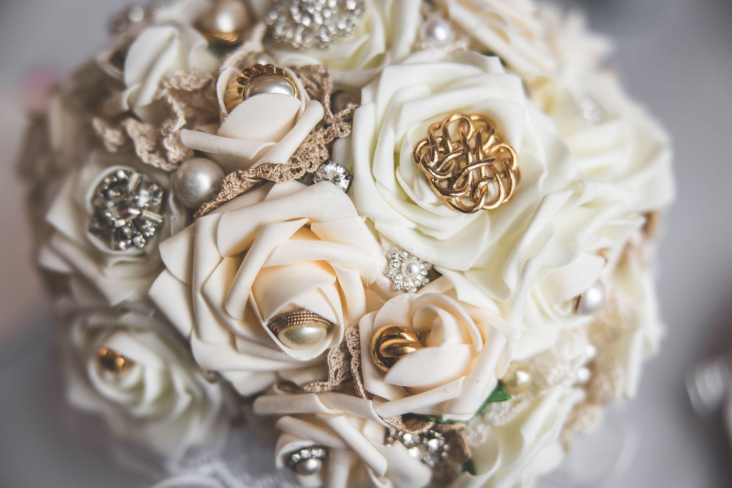 Close up of elegant white roses with crystal embellishments in a bridal bouquet.