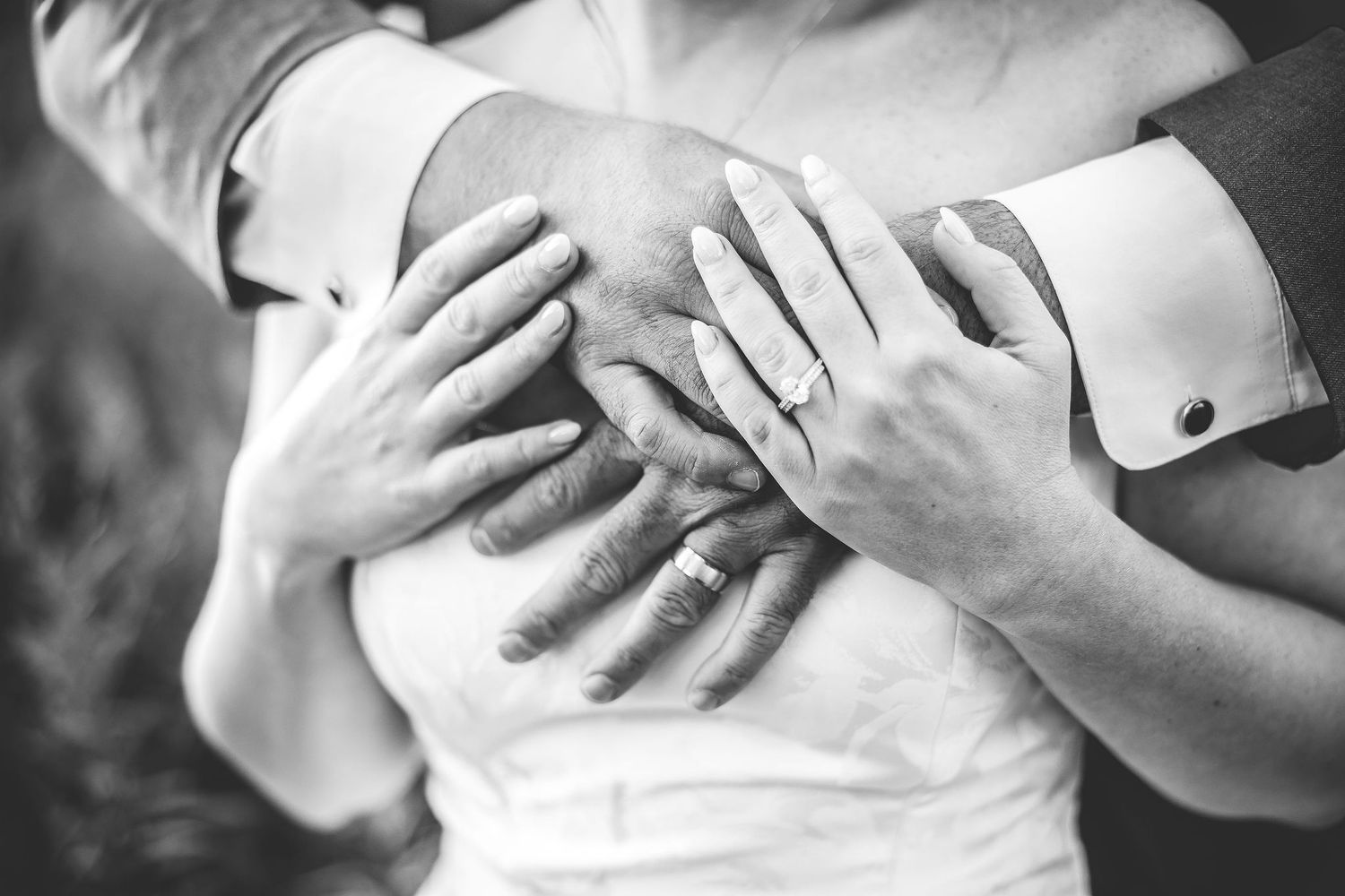 Black and white detail shots of hands and rings during an emotional wedding moment.