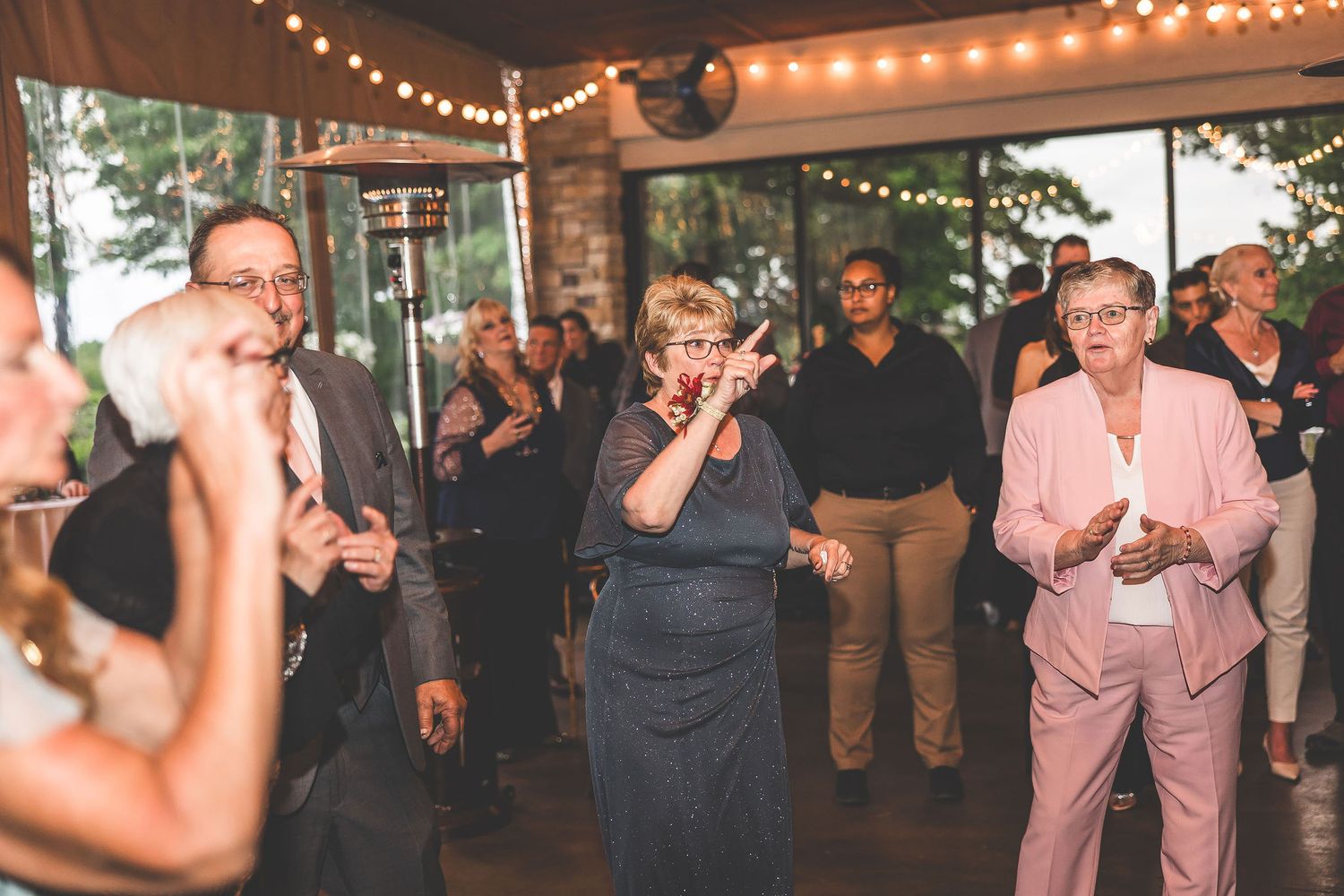 Wedding reception dance floor filled with guests under romantic string lighting.