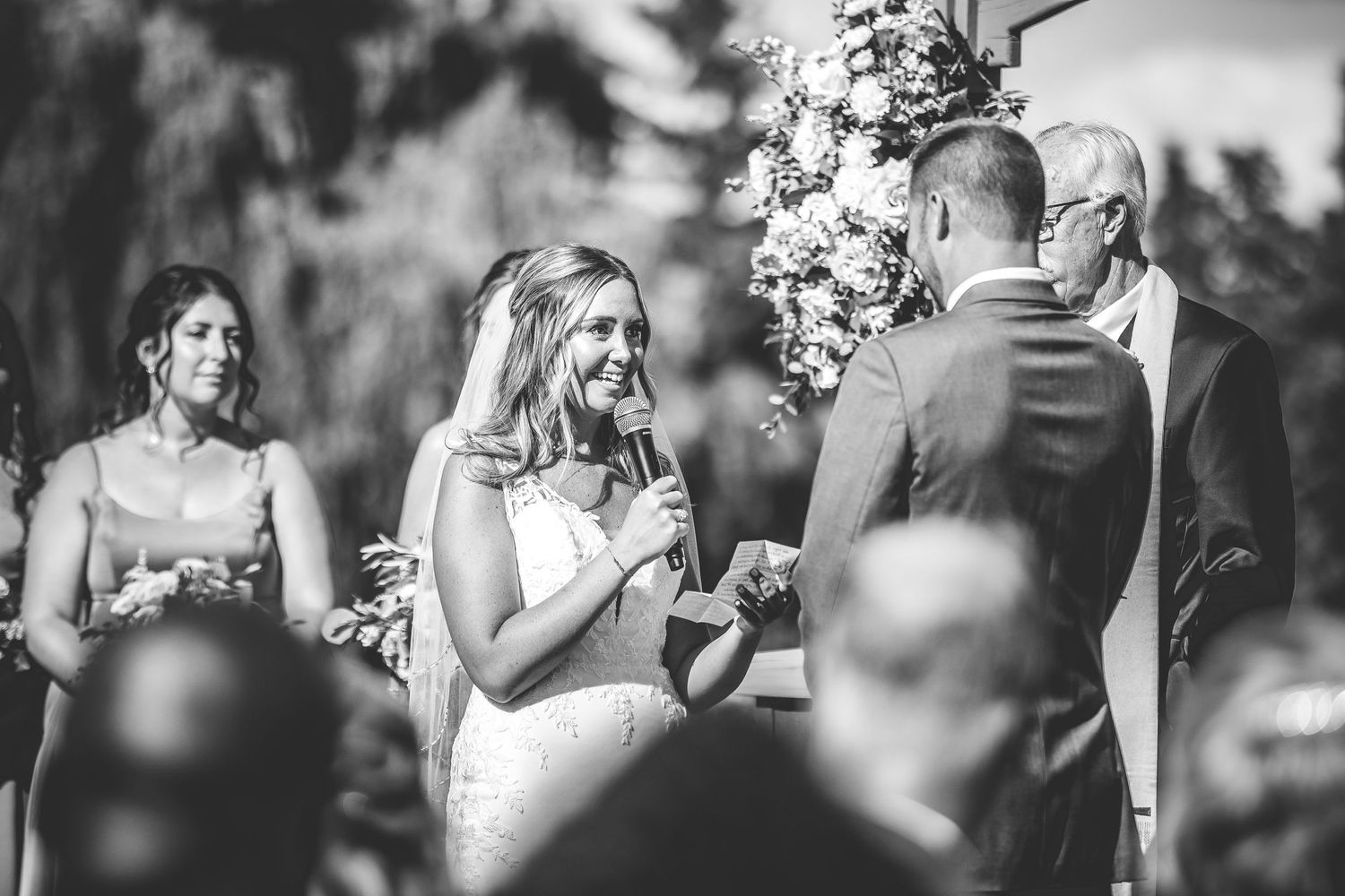 A candid black and white capture of a wedding ceremony with guests gathered outdoors.