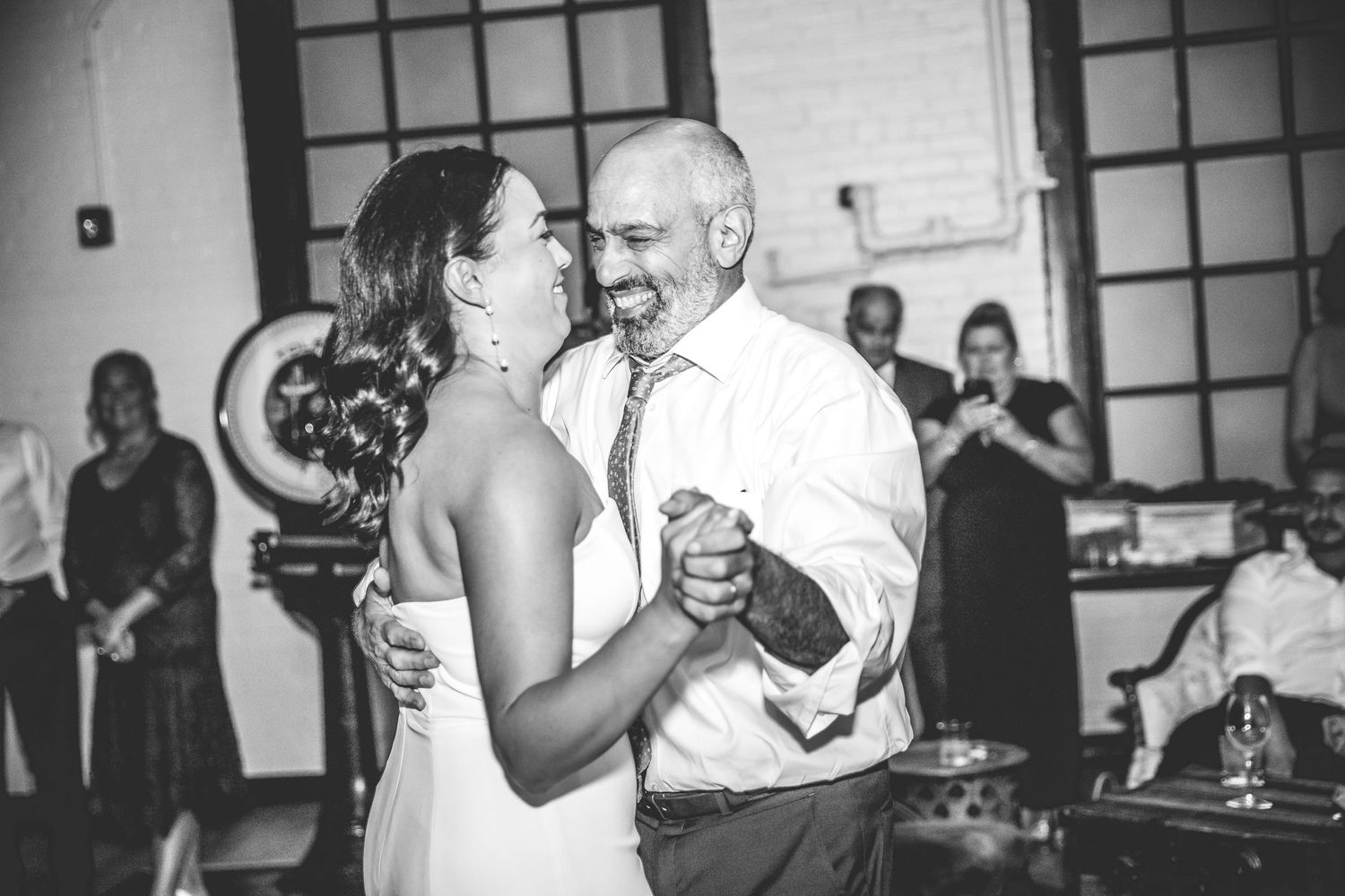 A black and white candid of a couple sharing a dance at their reception.
