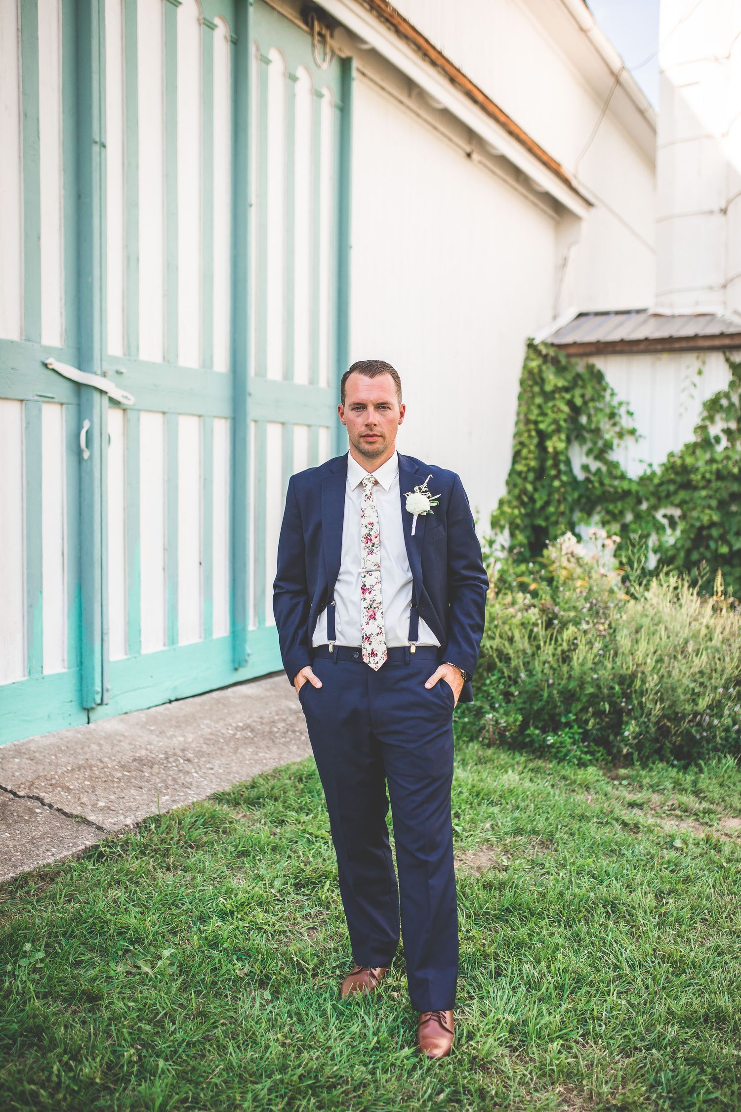 Groomsmen in navy suits pose individually against mint green striped architectural backdrop.