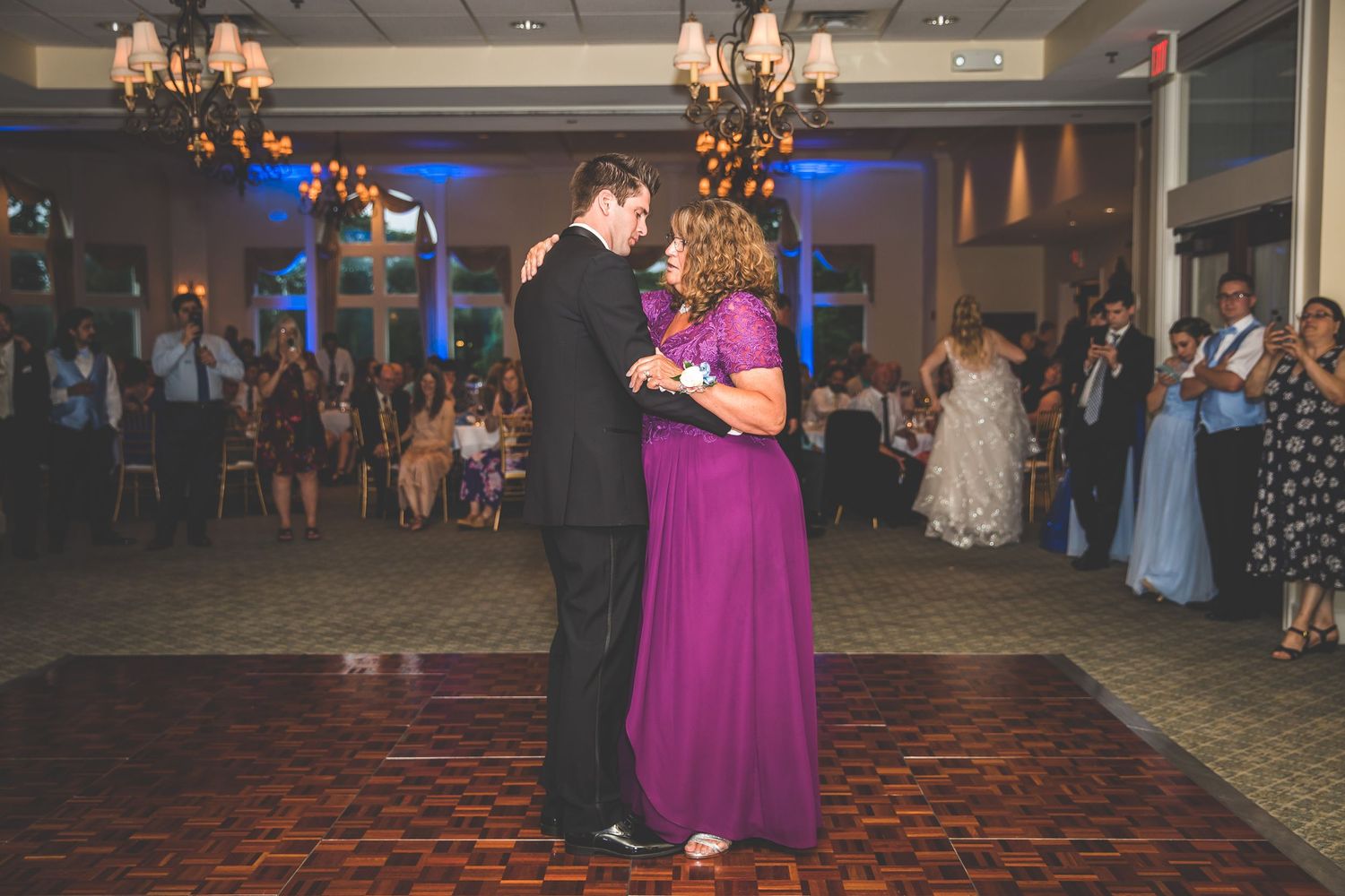 Elegant ballroom dance scene with formal attire and decorative lighting at a wedding reception.