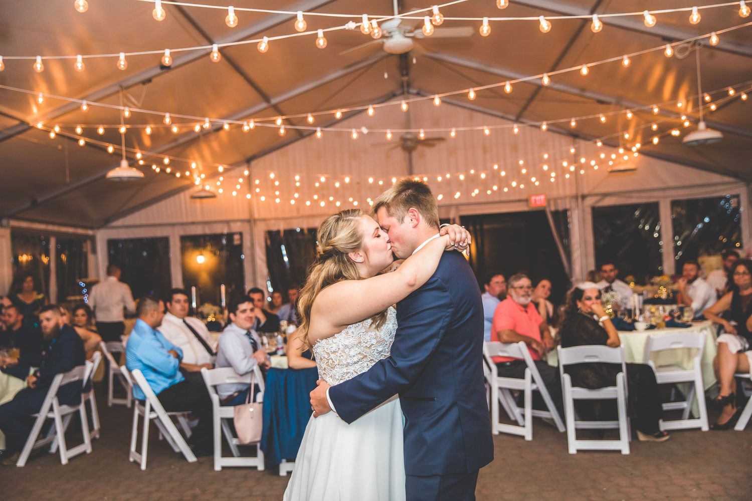 String lights illuminate an outdoor wedding reception as guests dance and celebrate.