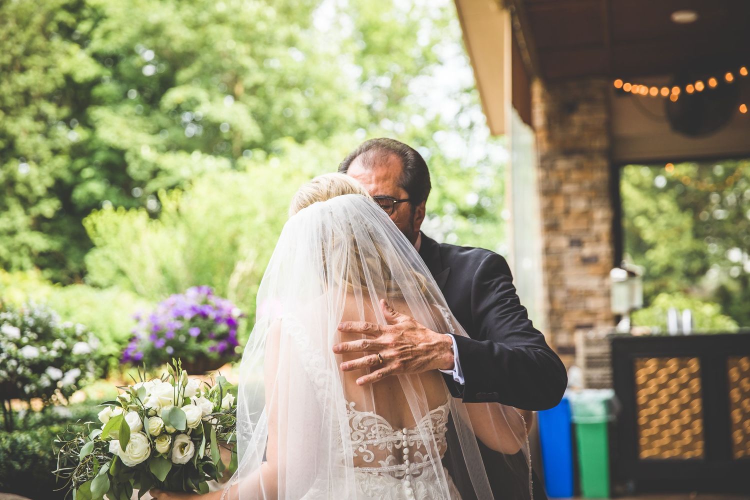 Emotional moment captured during outdoor wedding ceremony with lush garden backdrop.