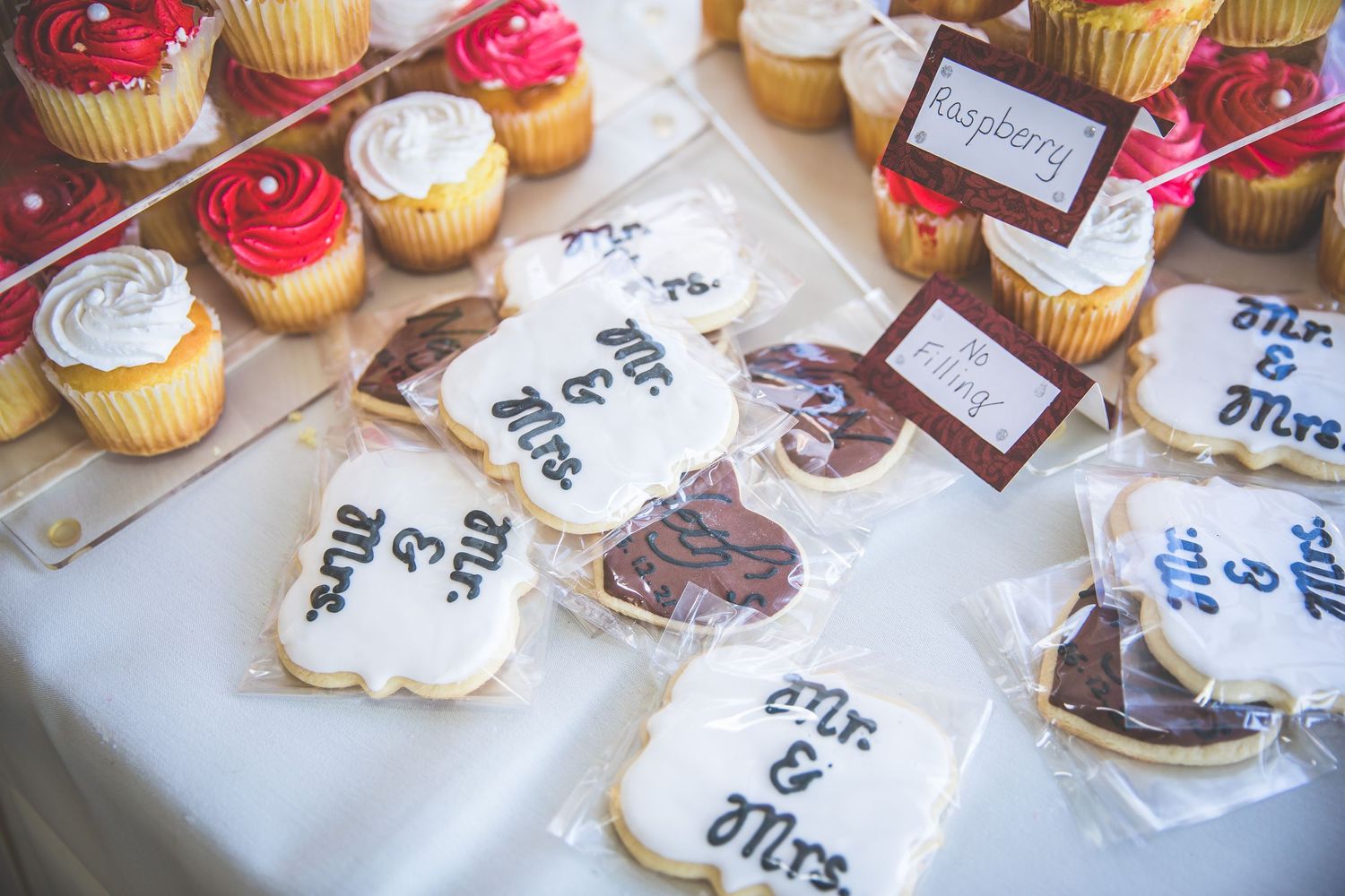 Wedding dessert table with decorated cupcakes and cookies featuring monogram designs.