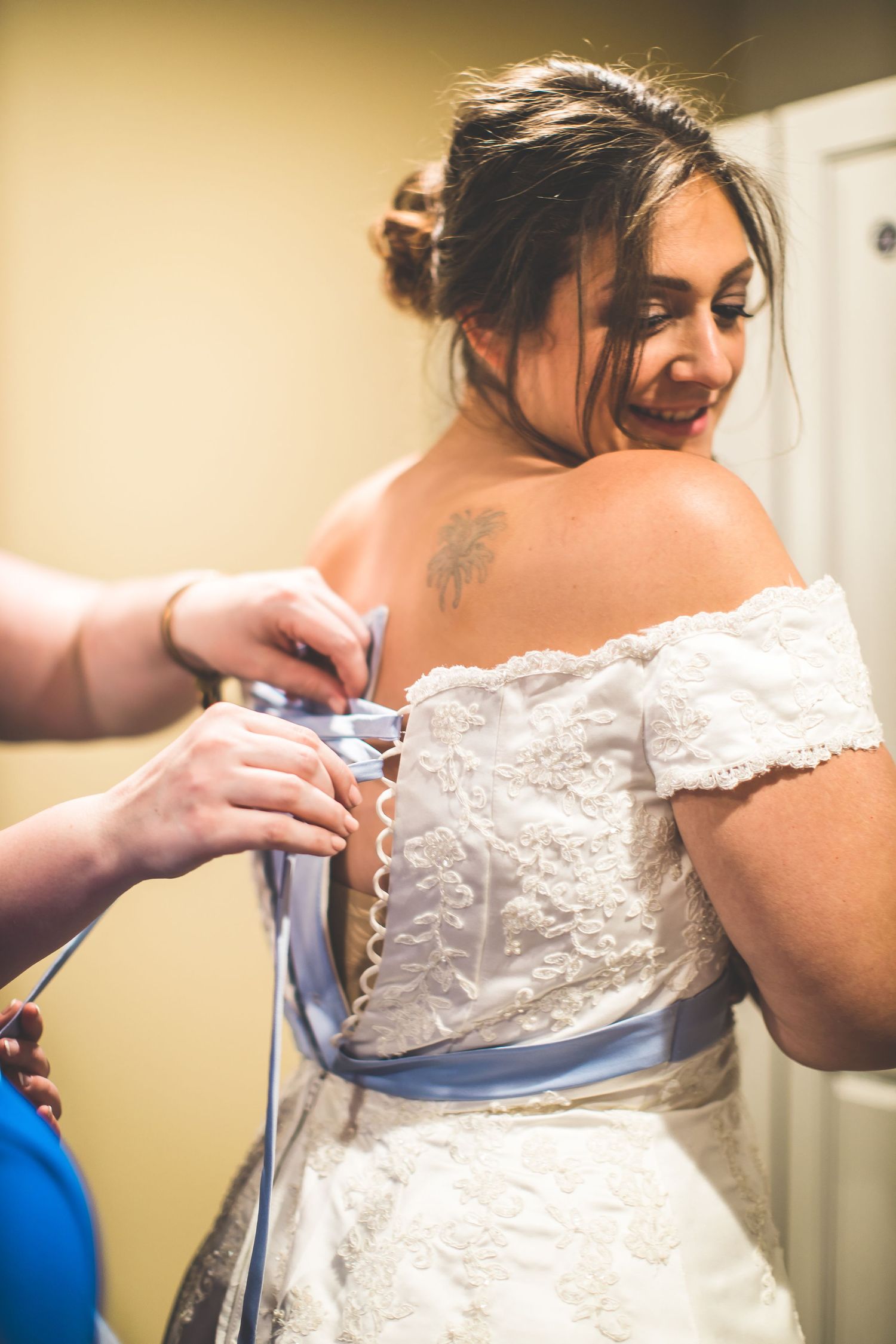 Close-up details of lacing up a white wedding dress with delicate lace details.