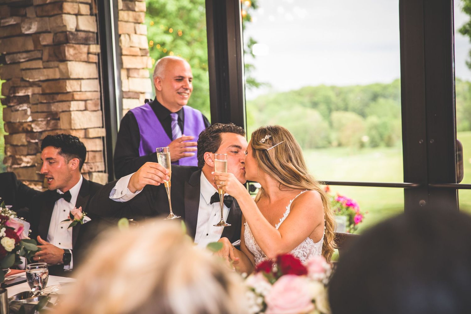 Wedding guests raise their glasses during a celebratory toast at a reception.