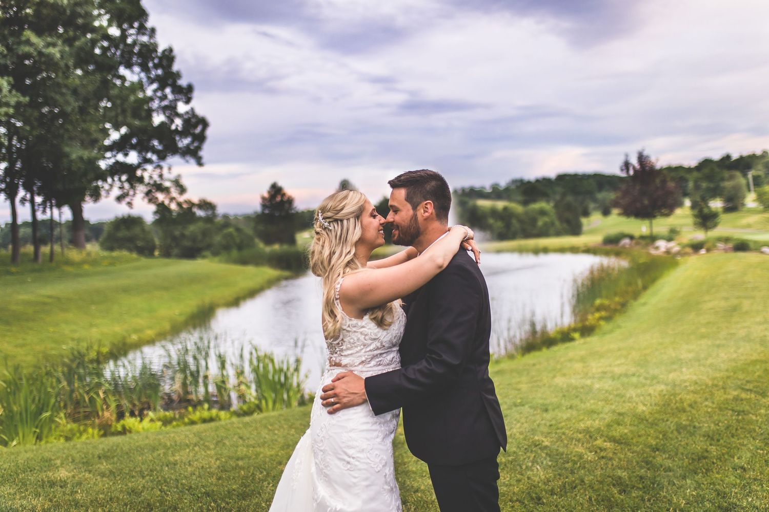Outdoor wedding photos taken near a scenic lake with cloudy sky backdrop.