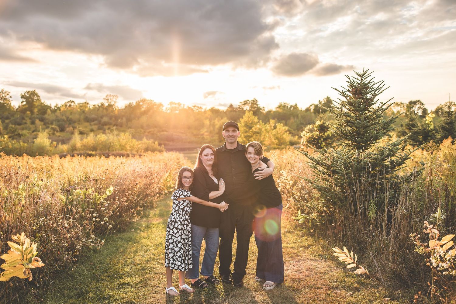 Silhouette of family at sunset in a golden field with dramatic sky.