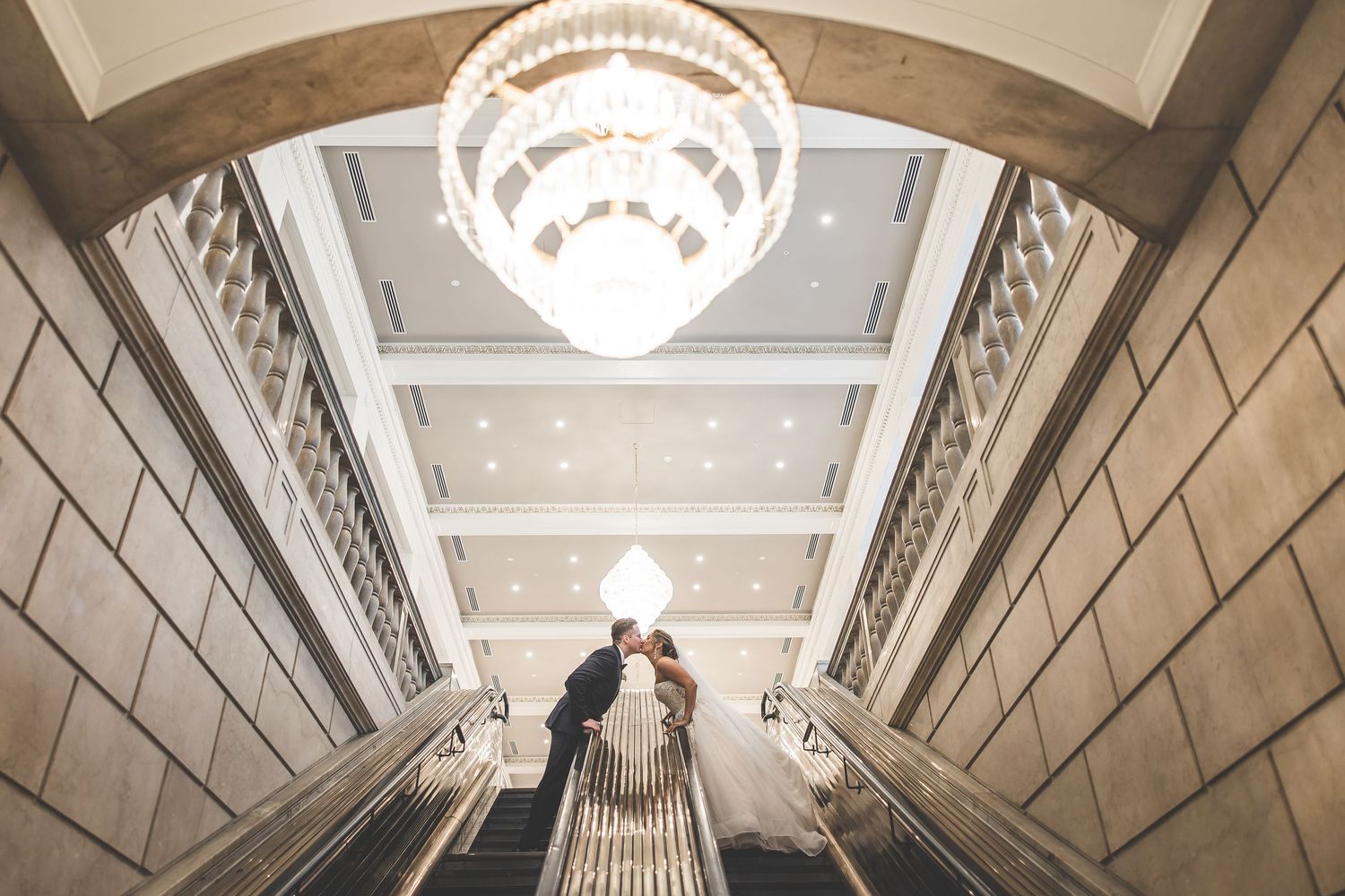 Grand chandelier hangs in an ornate architectural space with marble columns.