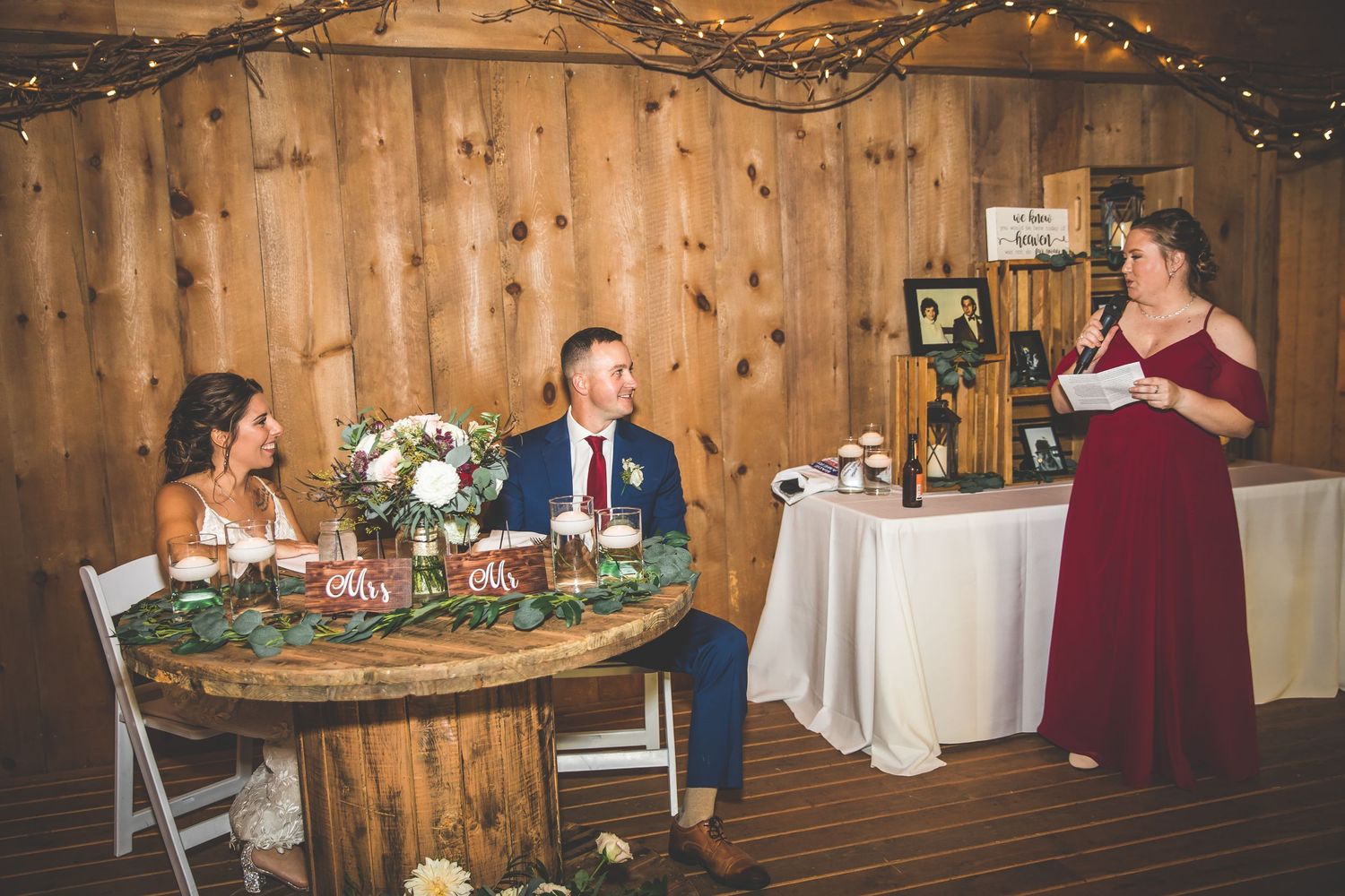 Wedding reception in a rustic wooden venue with table decorations and speech being given.