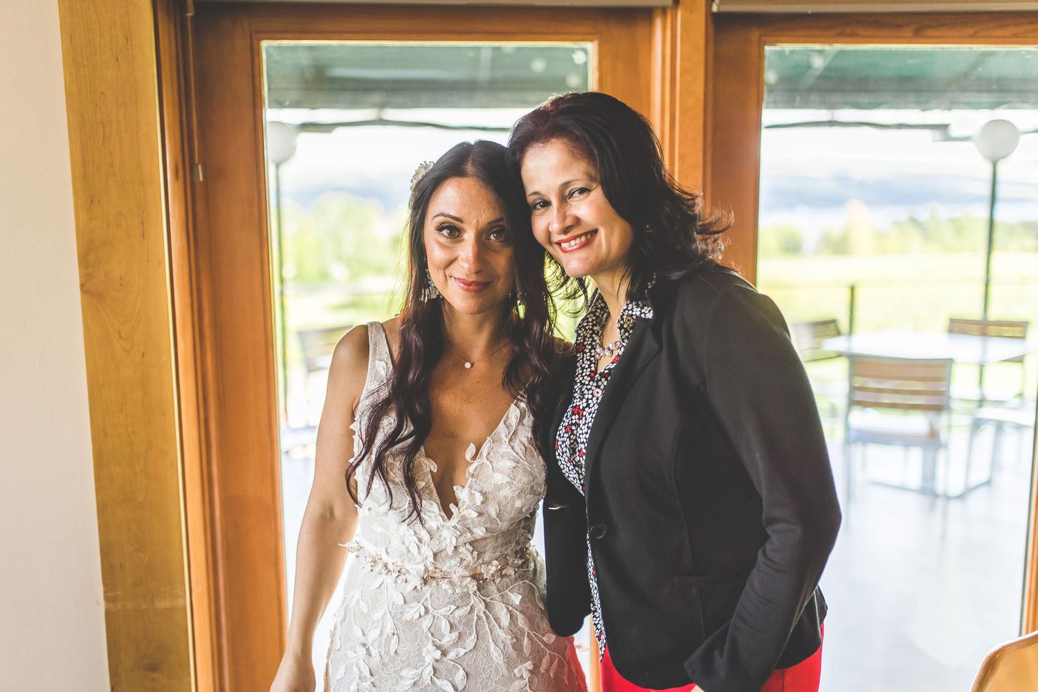 Wedding celebration with guests posing together in front of large windows.