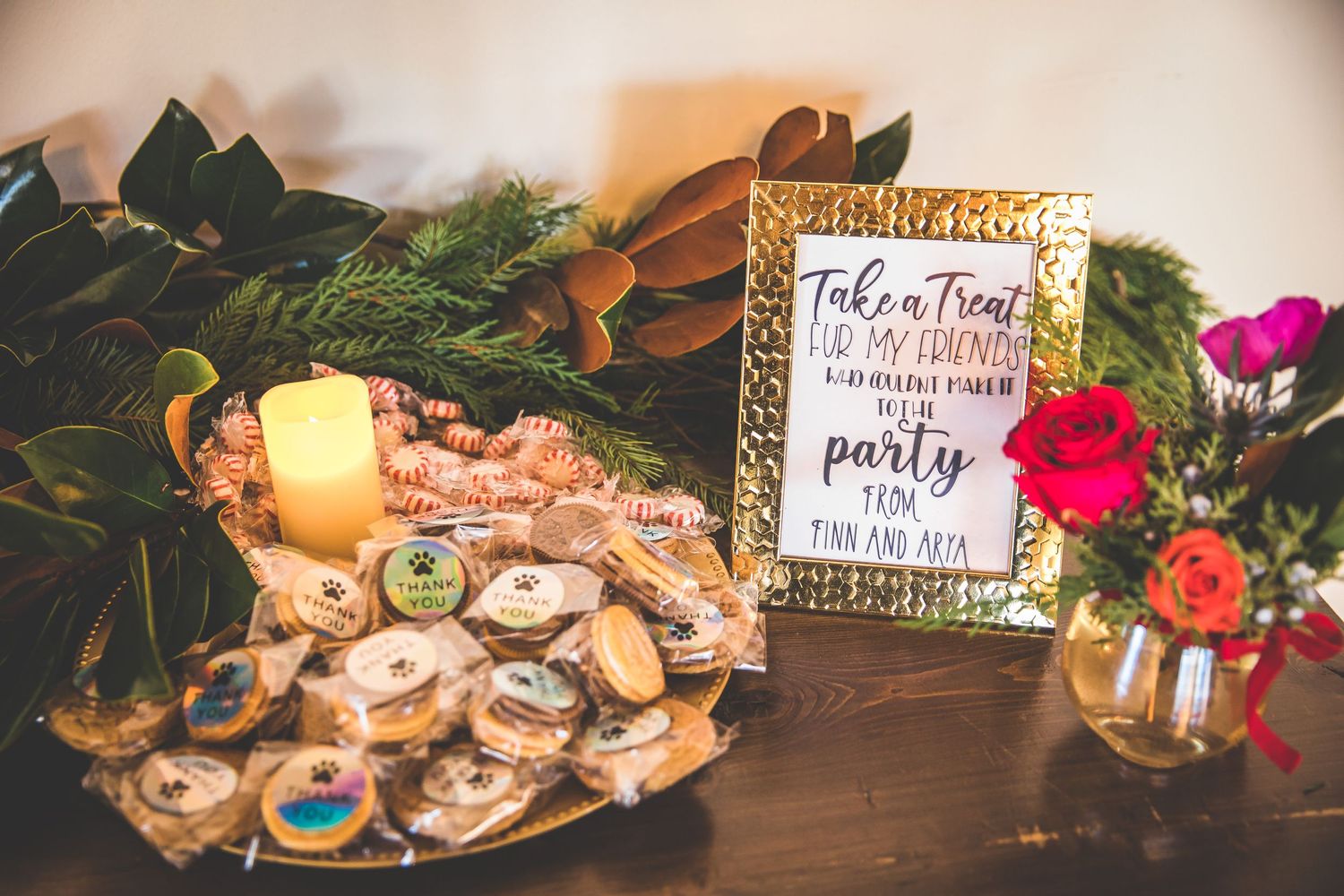 Wedding dessert table with cookies and treats decorated with holiday greenery and signage.