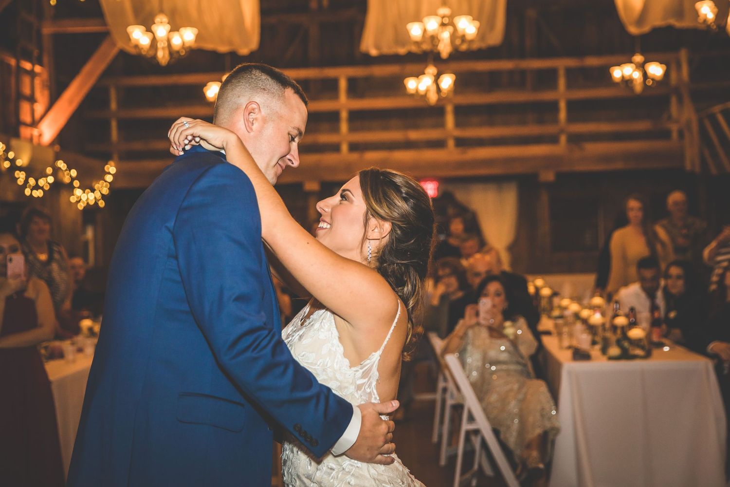 Romantic dance moments captured in warmly lit rustic barn reception venue.