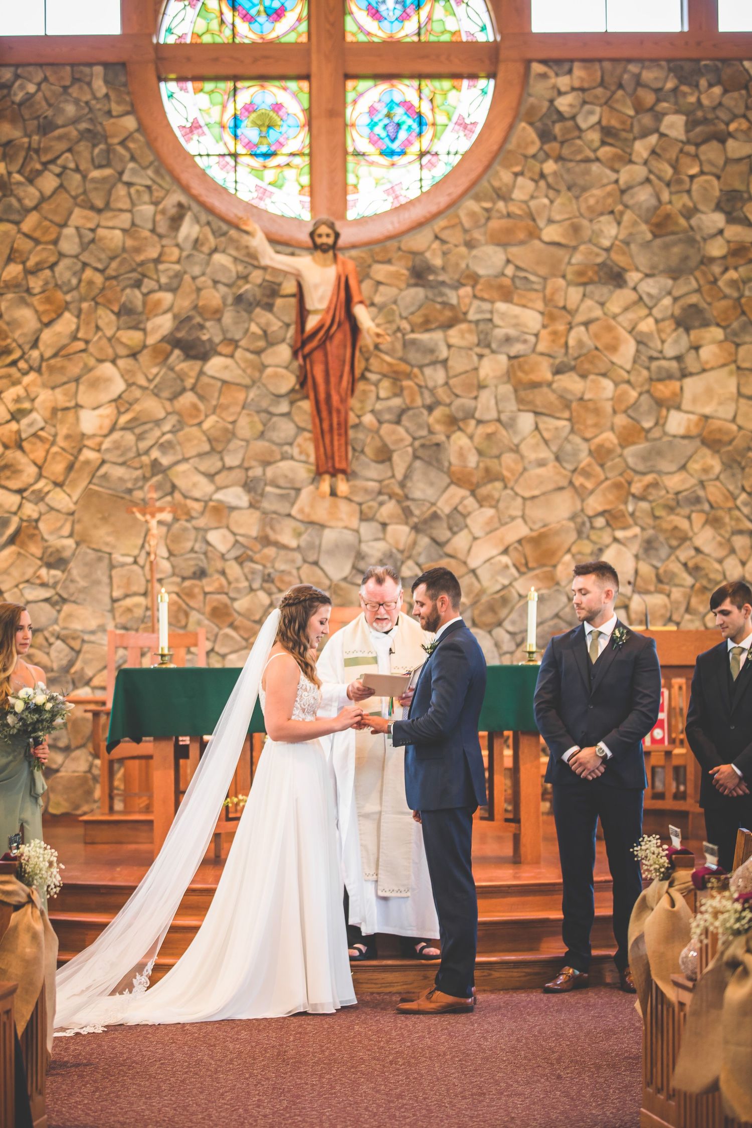 Wedding ceremony sequence showing exchange of vows in front of stained glass windows.