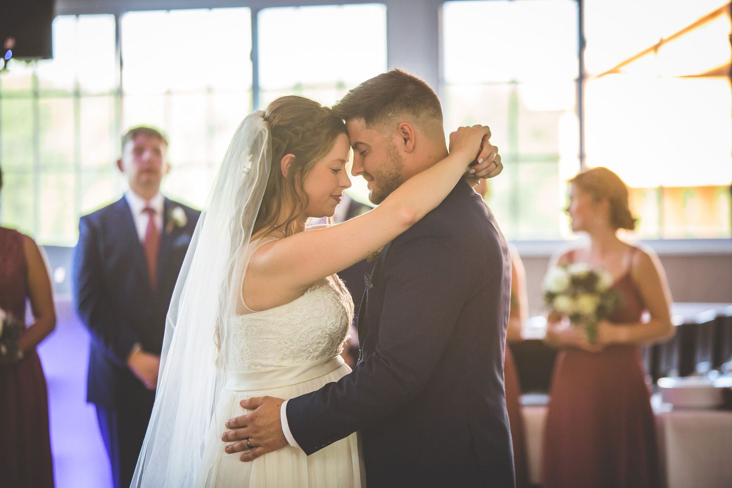 Romantic first dance between newlyweds in a softly lit reception venue.