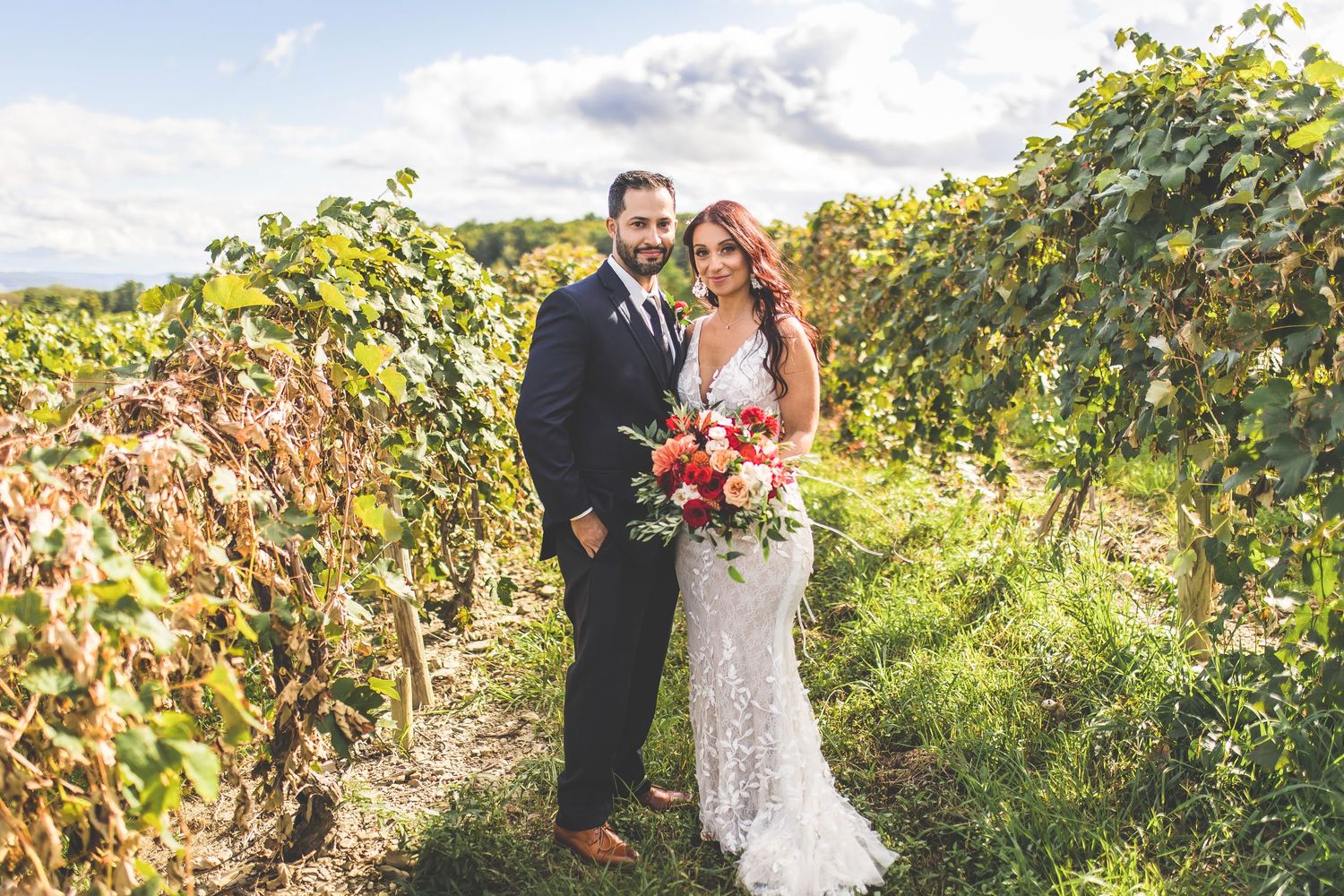 A romantic wedding photoshoot in a scenic vineyard during golden hour with lush grapevines in the background.