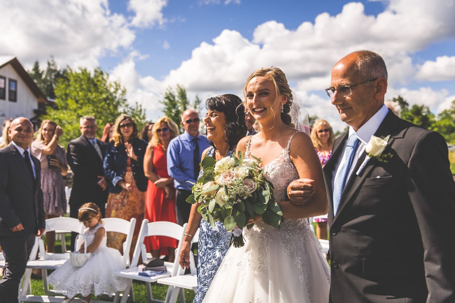 An outdoor wedding ceremony under blue skies with white chairs and mountain scenery.