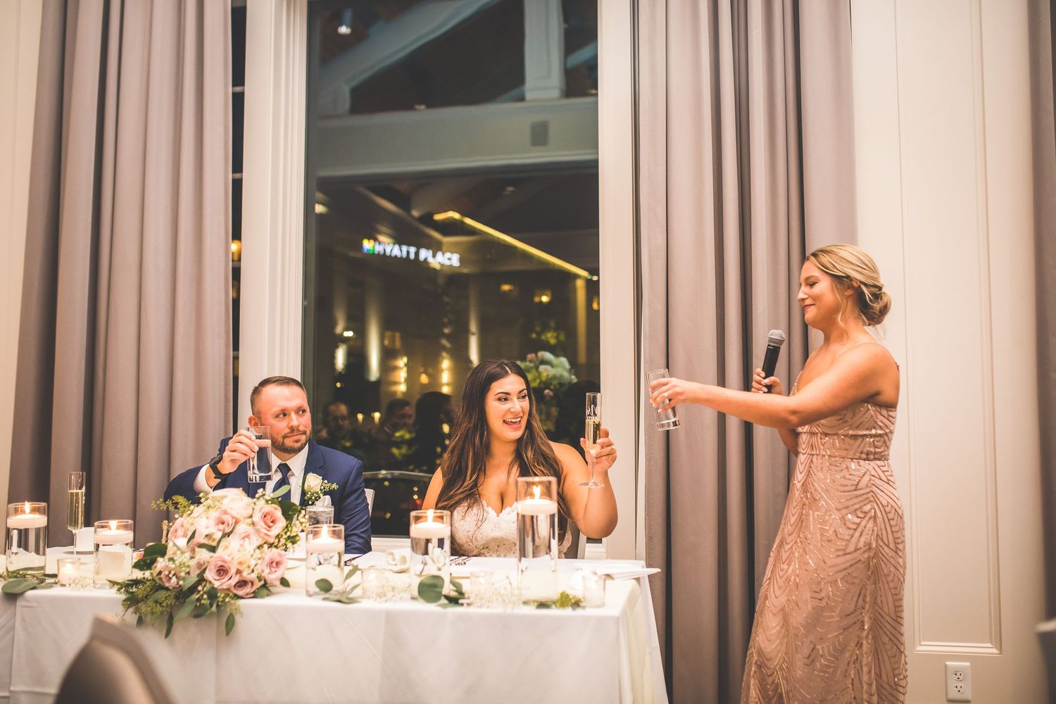 Wedding reception dinner setup with elegant table settings and white drapes.