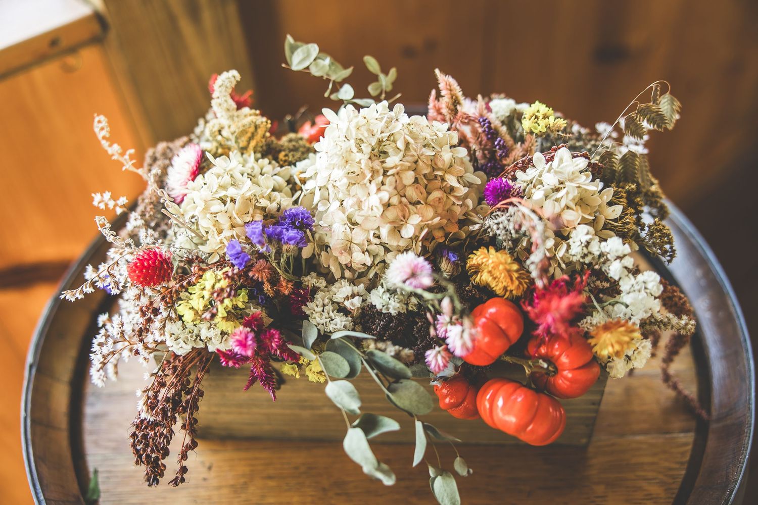 Dried flower arrangements with wildflowers and autumn colors displayed on dark wooden surface.