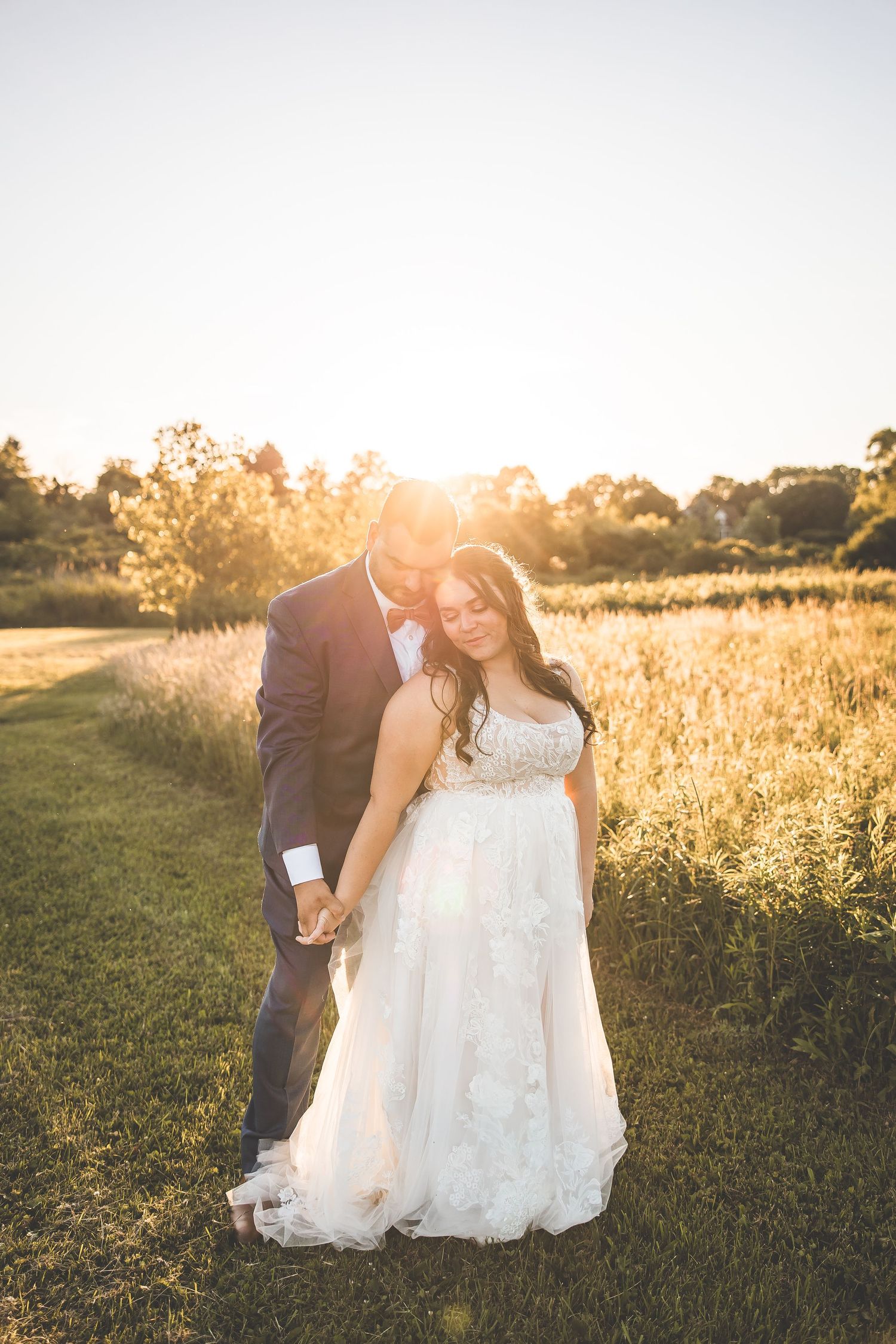 Sunset wedding portraits in a golden field with soft natural lighting.