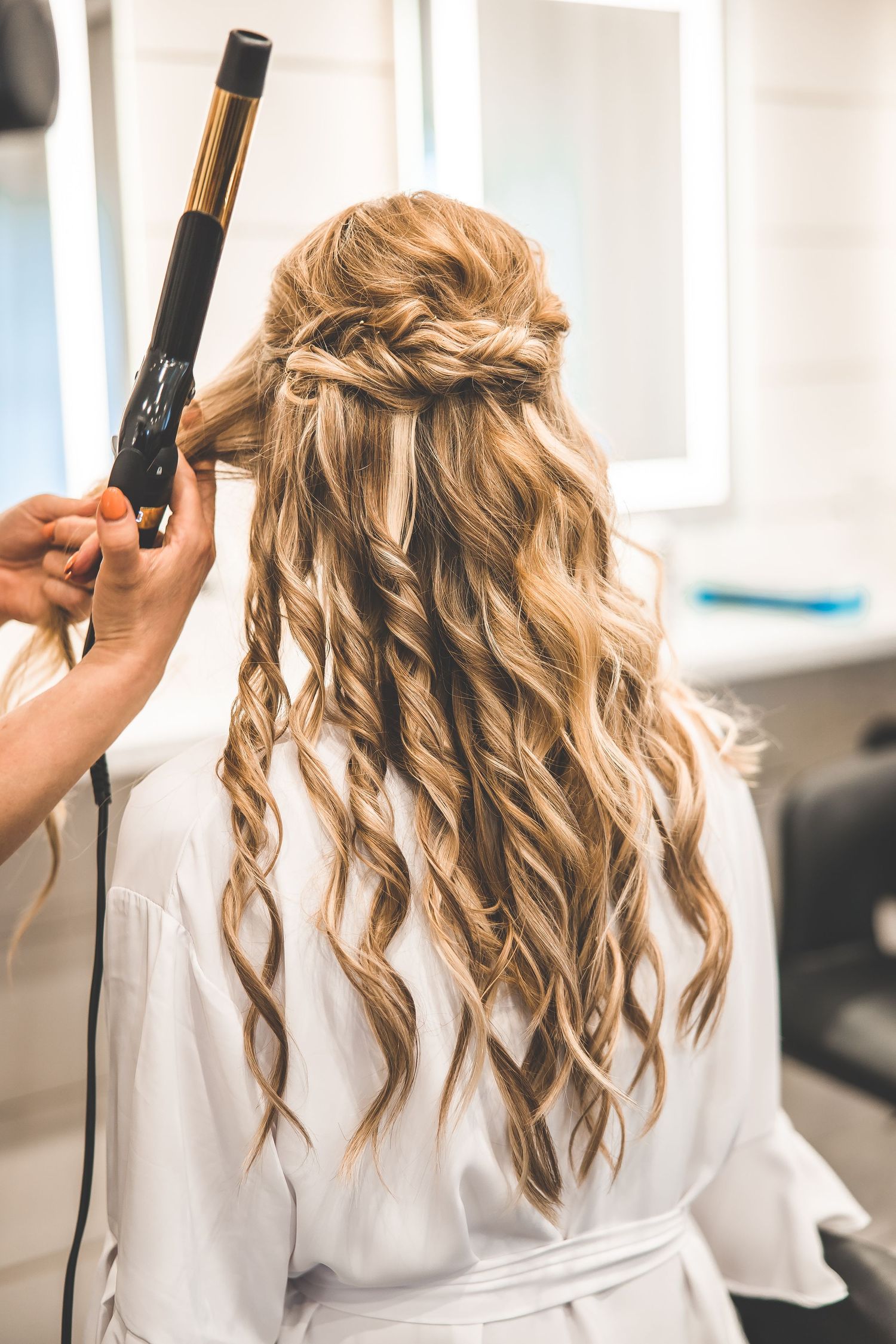 Hair styling session showing curling technique on blonde wavy hair.