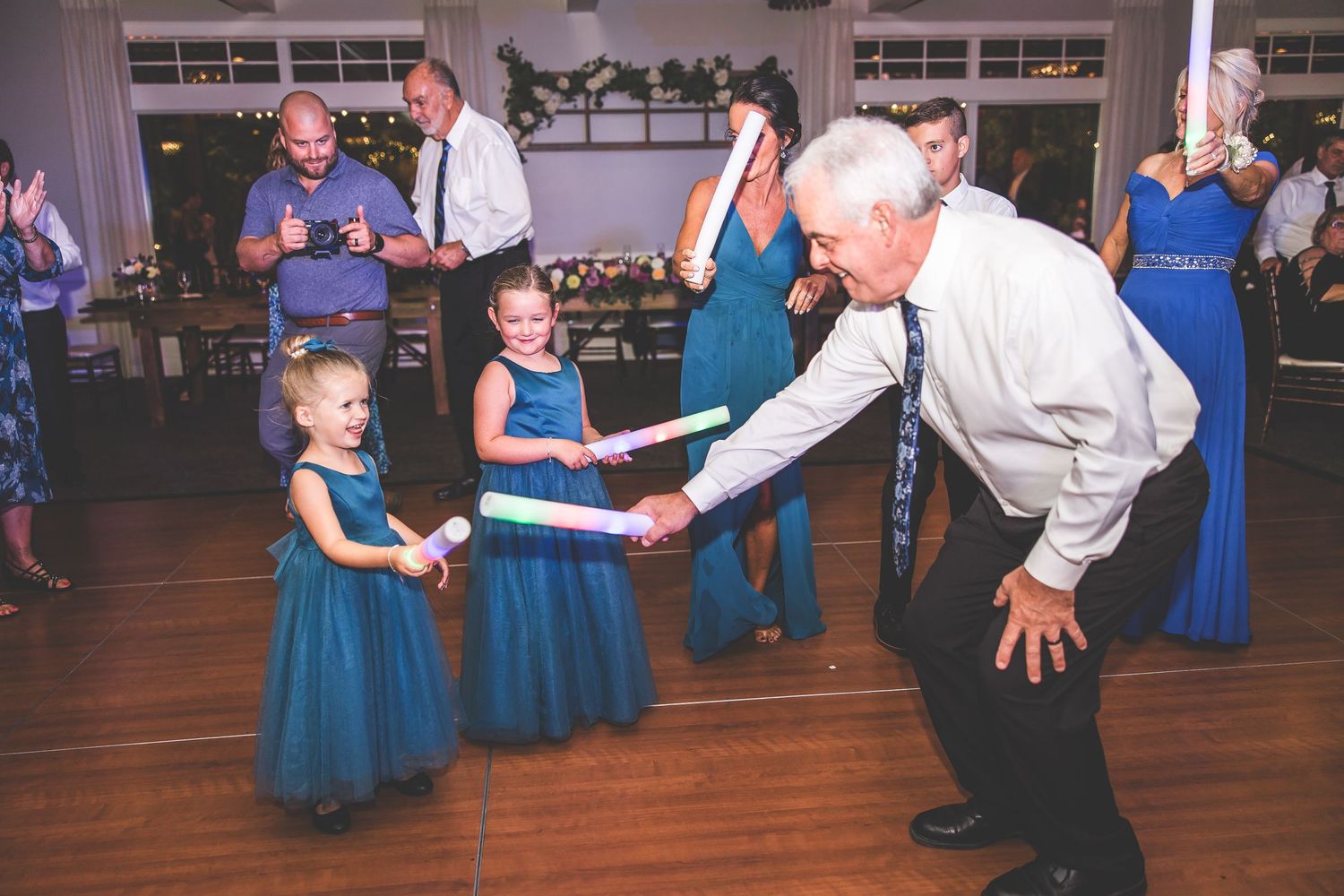 Wedding guests dancing and celebrating on wooden dance floor at reception venue.