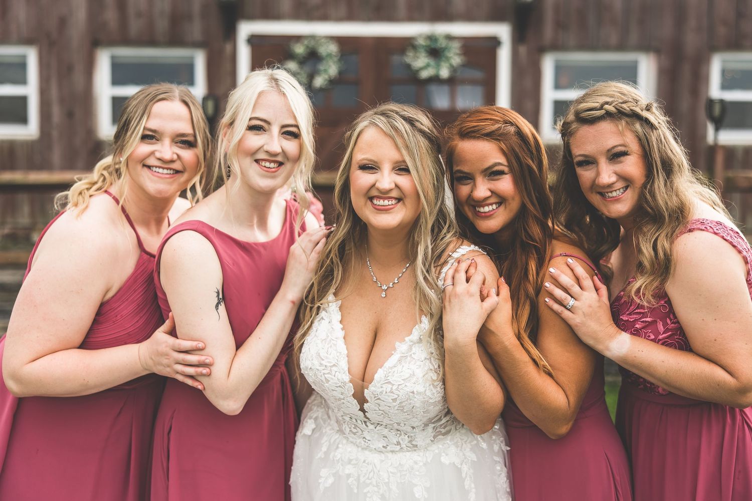 Candid moment of bridal party laughing together in front of rustic barn setting.